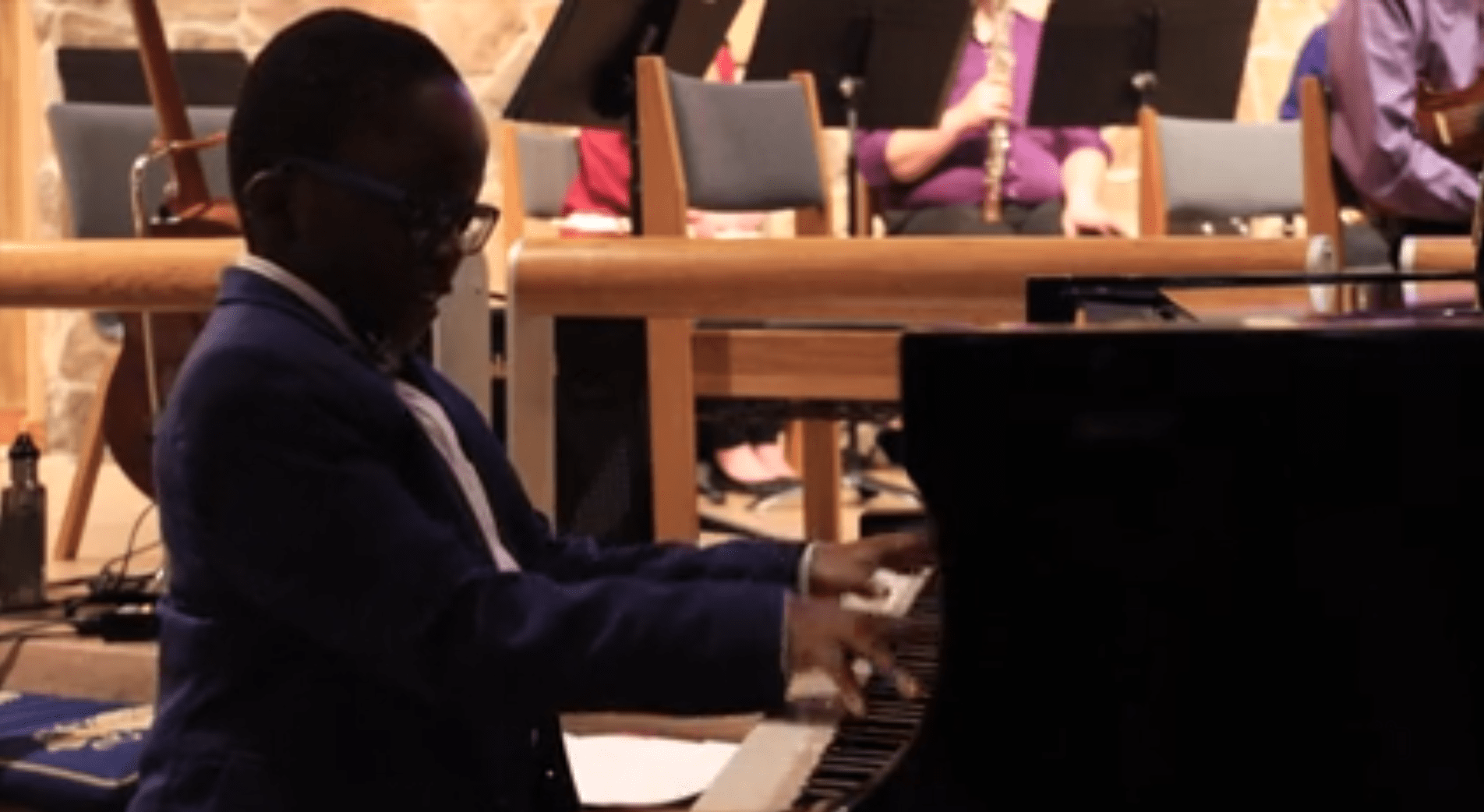 A young boy in a suit plays a piano