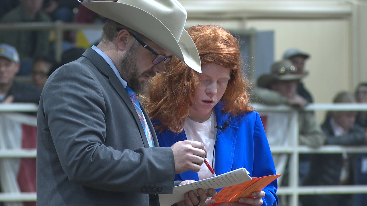 A young girl stands beside a man in a cowboy hat at the National Western Stock Show