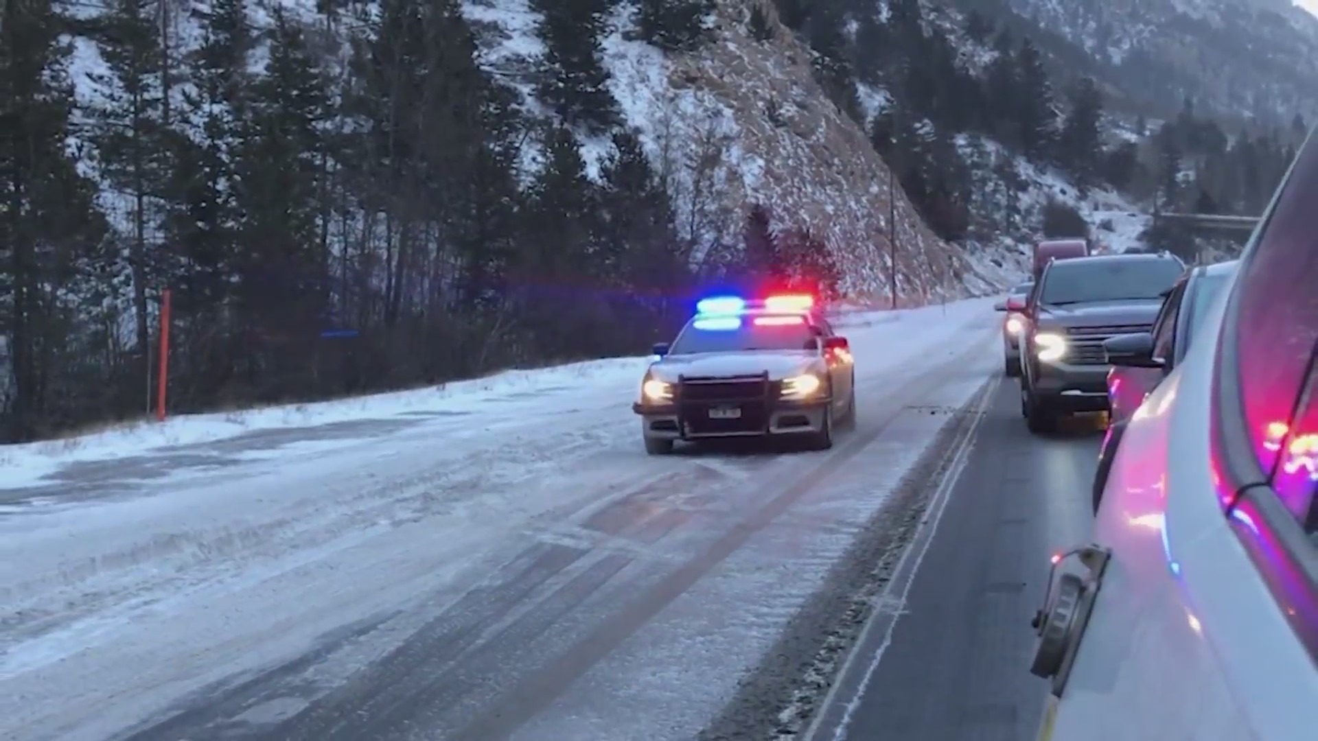 A Colorado State Patrol car on a snowy Interstate 70 during a gloomy day