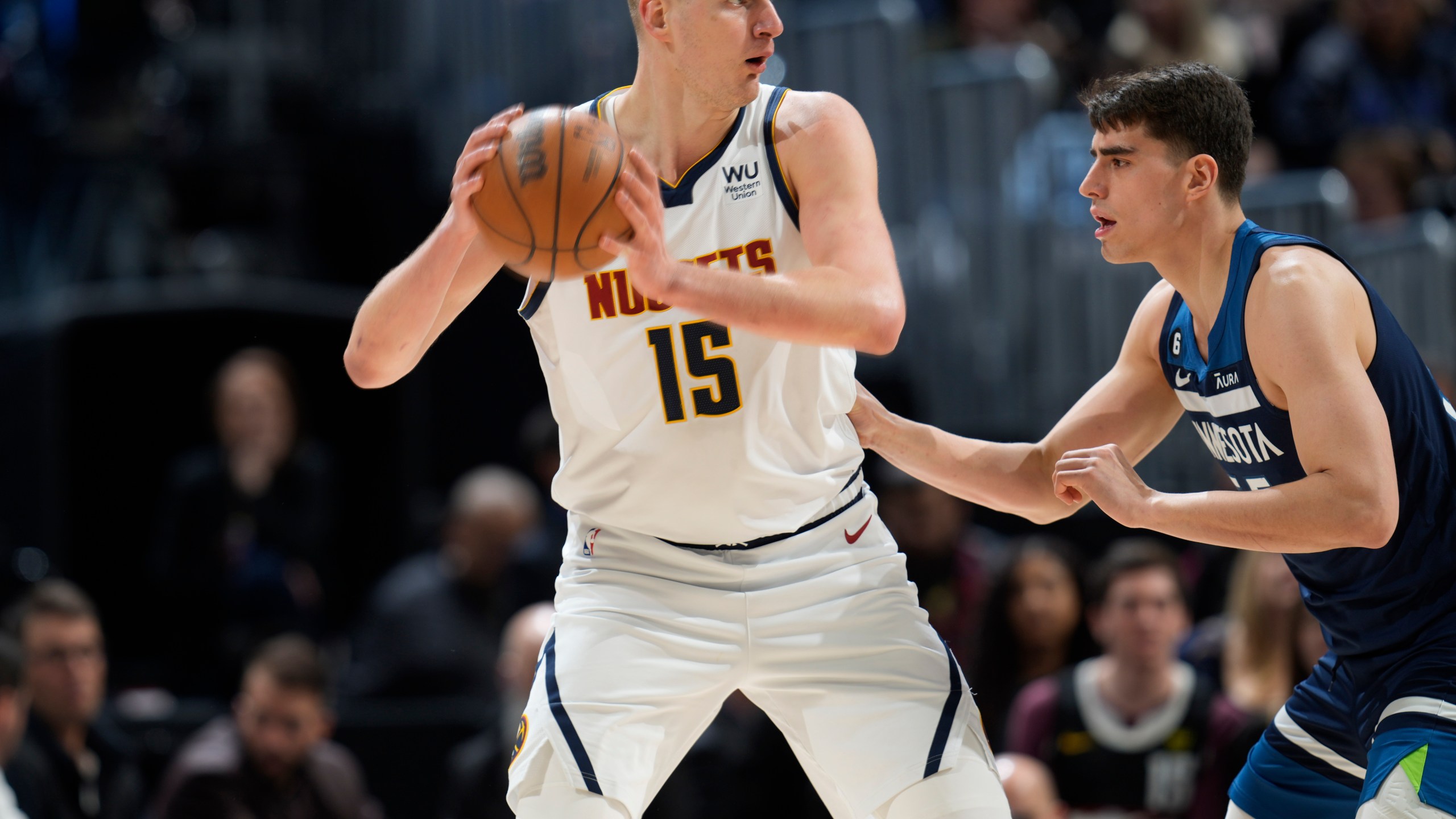 Denver Nuggets center Nikola Jokic, left, looks to pass the ball as Minnesota Timberwolves center Luka Garza defends