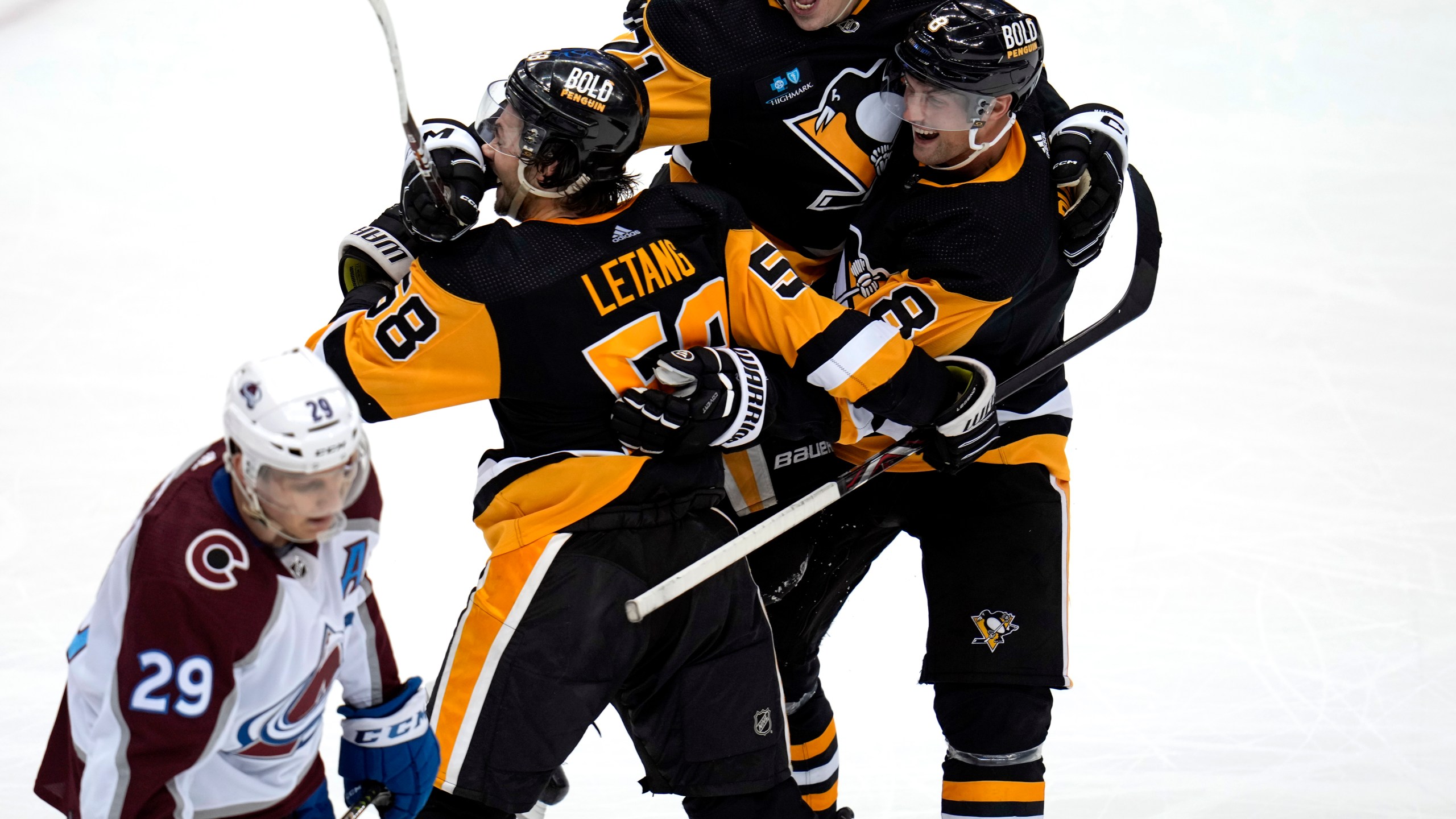 Pittsburgh Penguins' Kris Letang (58) celebrates his overtime goal with Evgeni Malkin (71) and Brian Dumoulin (8) as Colorado Avalanche's Nathan MacKinnon (29) skates off the ice