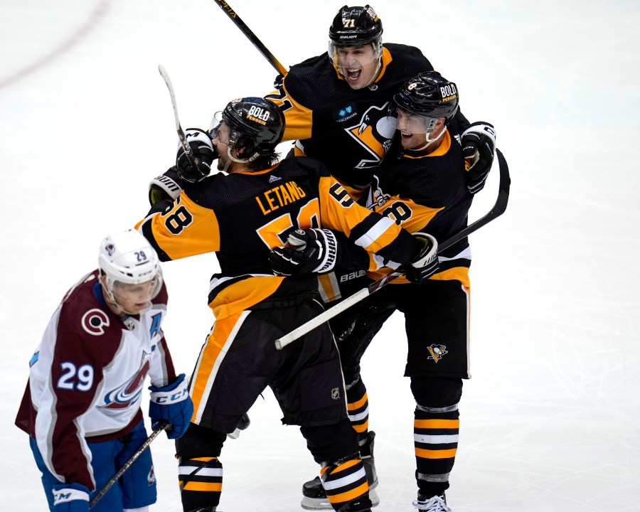 Pittsburgh Penguins' Kris Letang (58) celebrates his overtime goal with Evgeni Malkin (71) and Brian Dumoulin (8) as Colorado Avalanche's Nathan MacKinnon (29) skates off the ice