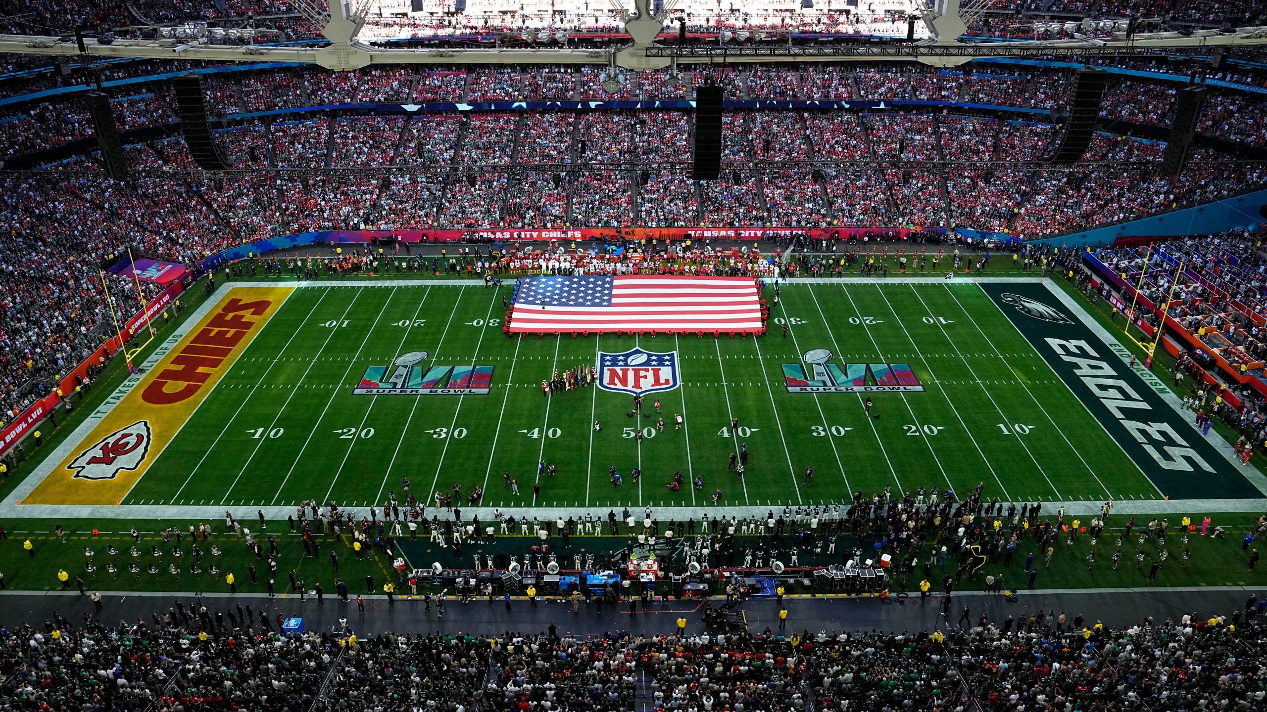 Wide angle of Super Bowl 57 field with large U.S. flag midfield and Chris Stapleton singing