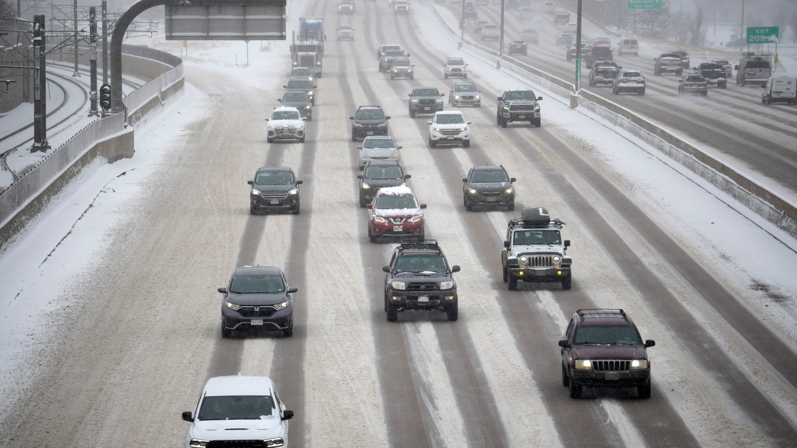 Motorists negotiate the southbound lanes of a snow-covered and icy Interstate 25 near the Steele Street overpass