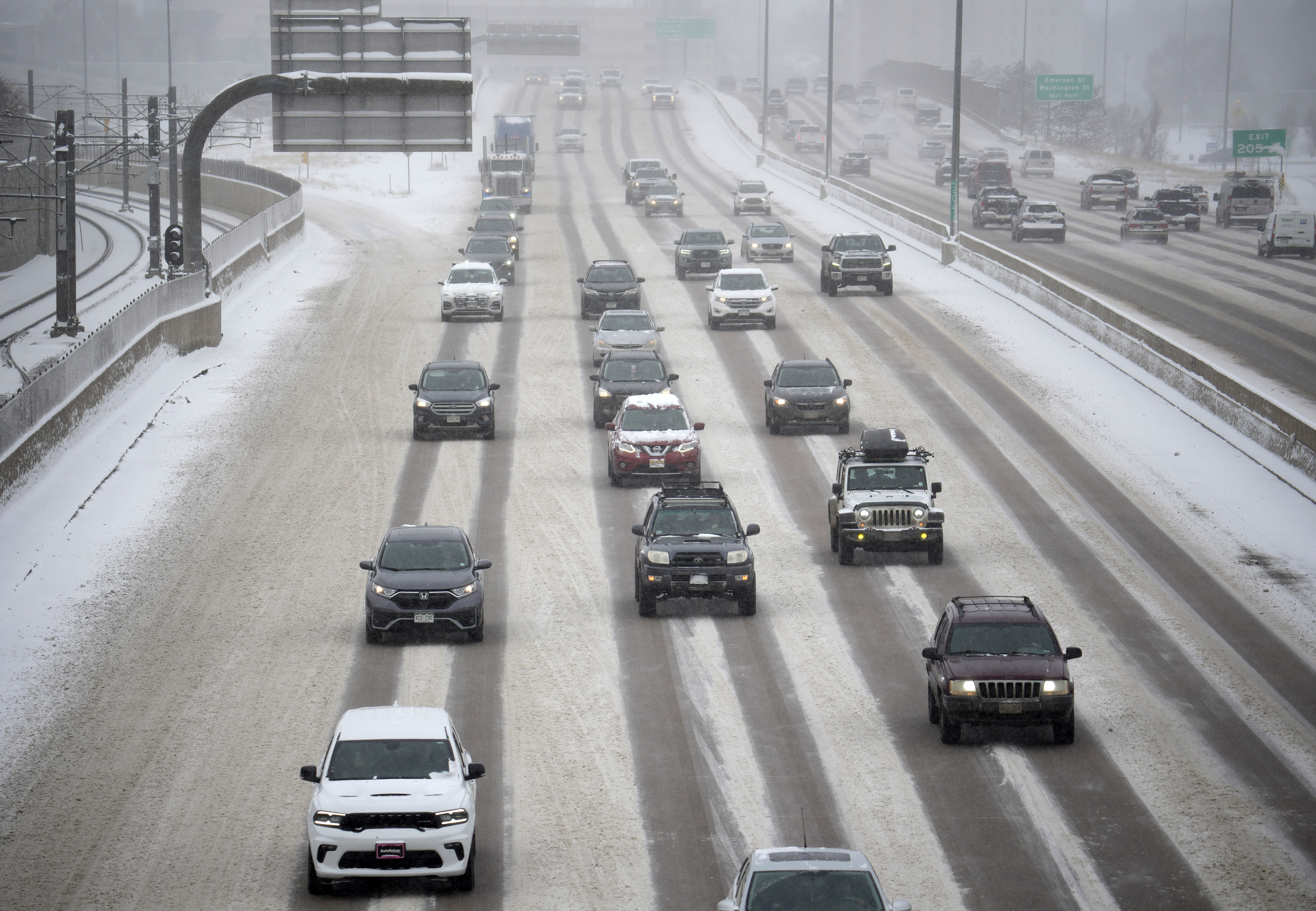 Motorists negotiate the southbound lanes of a snow-covered and icy Interstate 25 near the Steele Street overpass