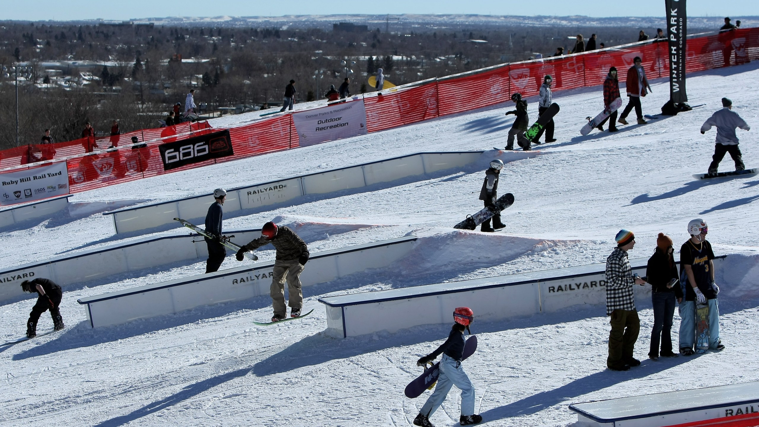 Snowboarders and skiers on the features at Ruby Hill Rail Yard park