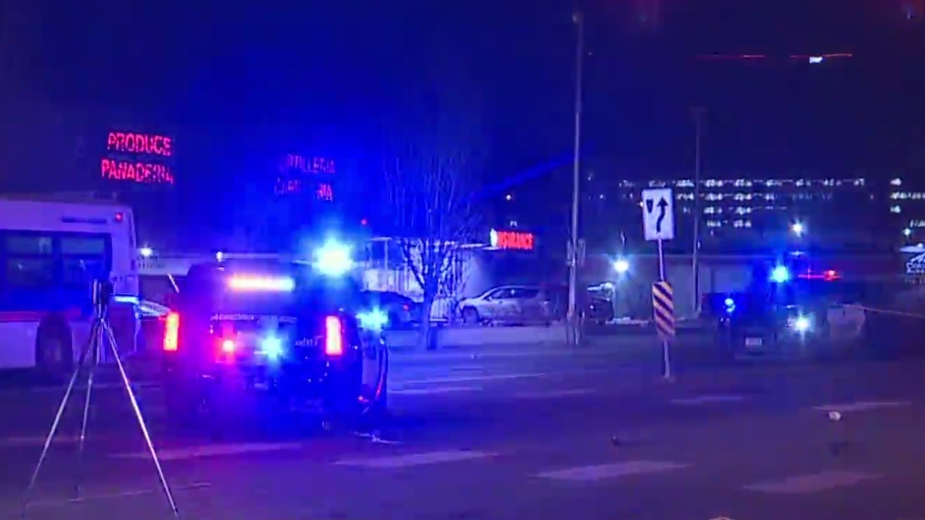 Two police vehicles in the middle of the road near a crosswalk with police tape blocking the area