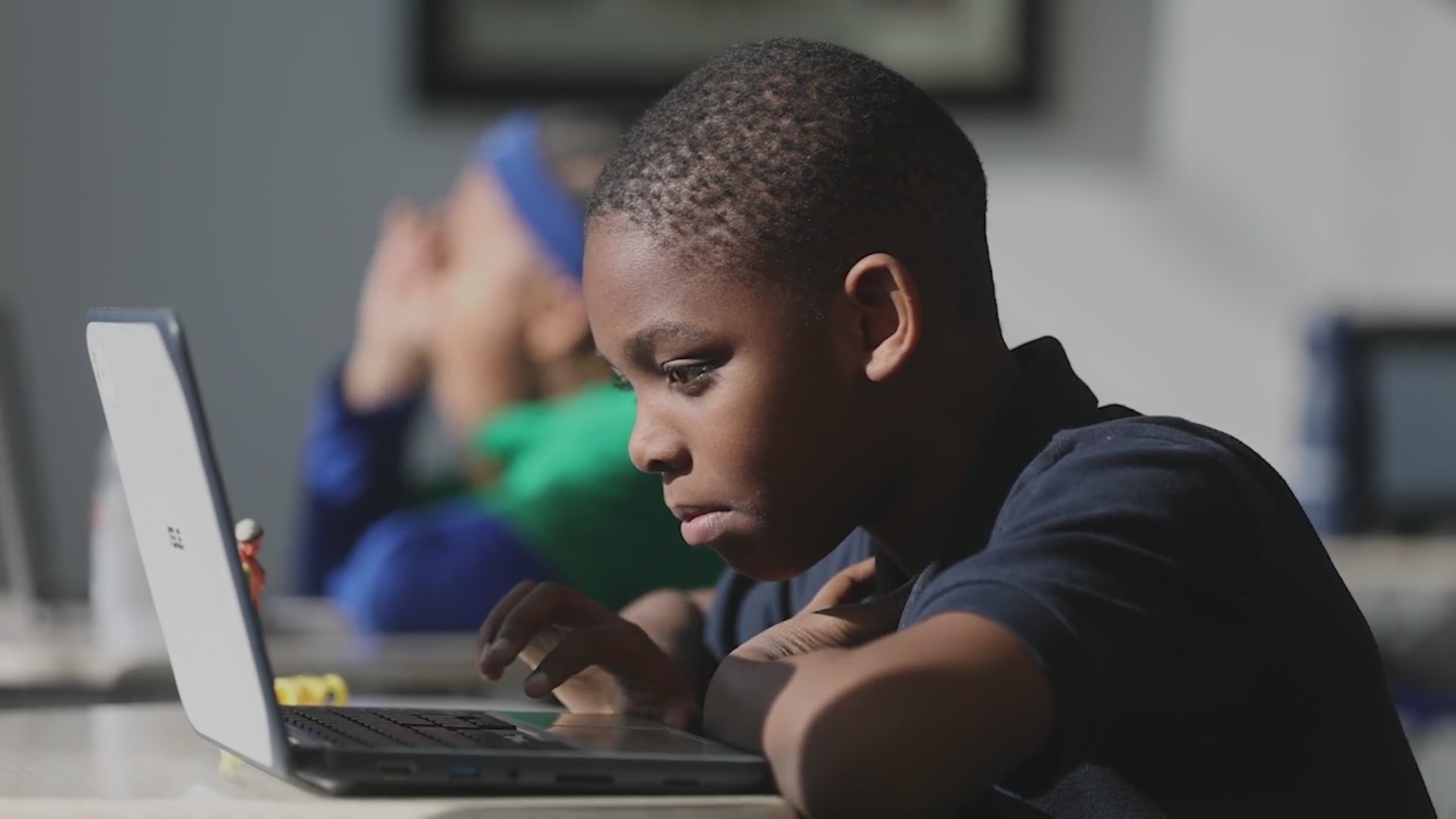 A young boy on a laptop at school