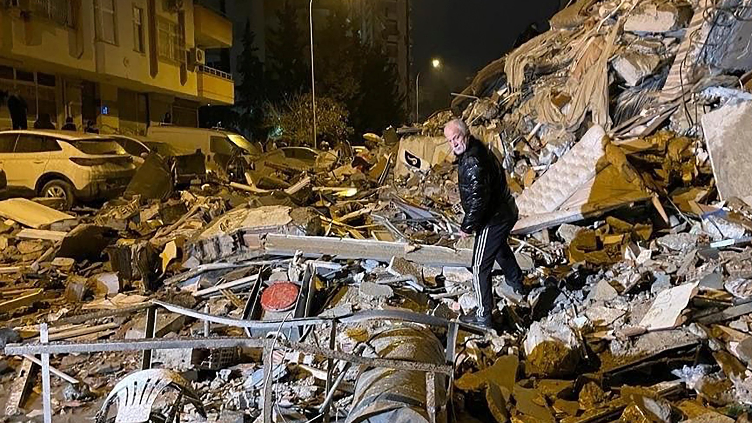 A man searches collapsed buildings