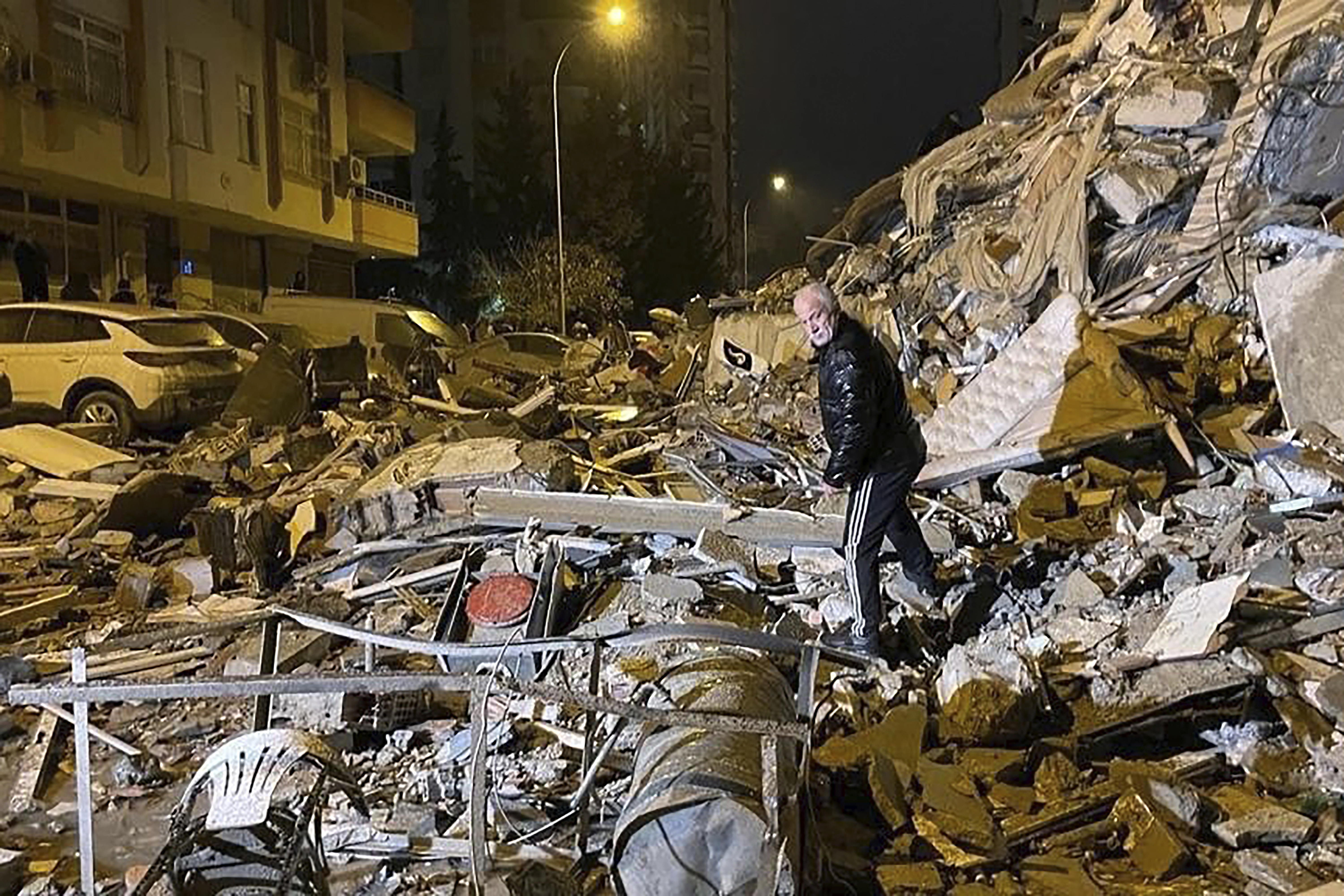 A man searches collapsed buildings