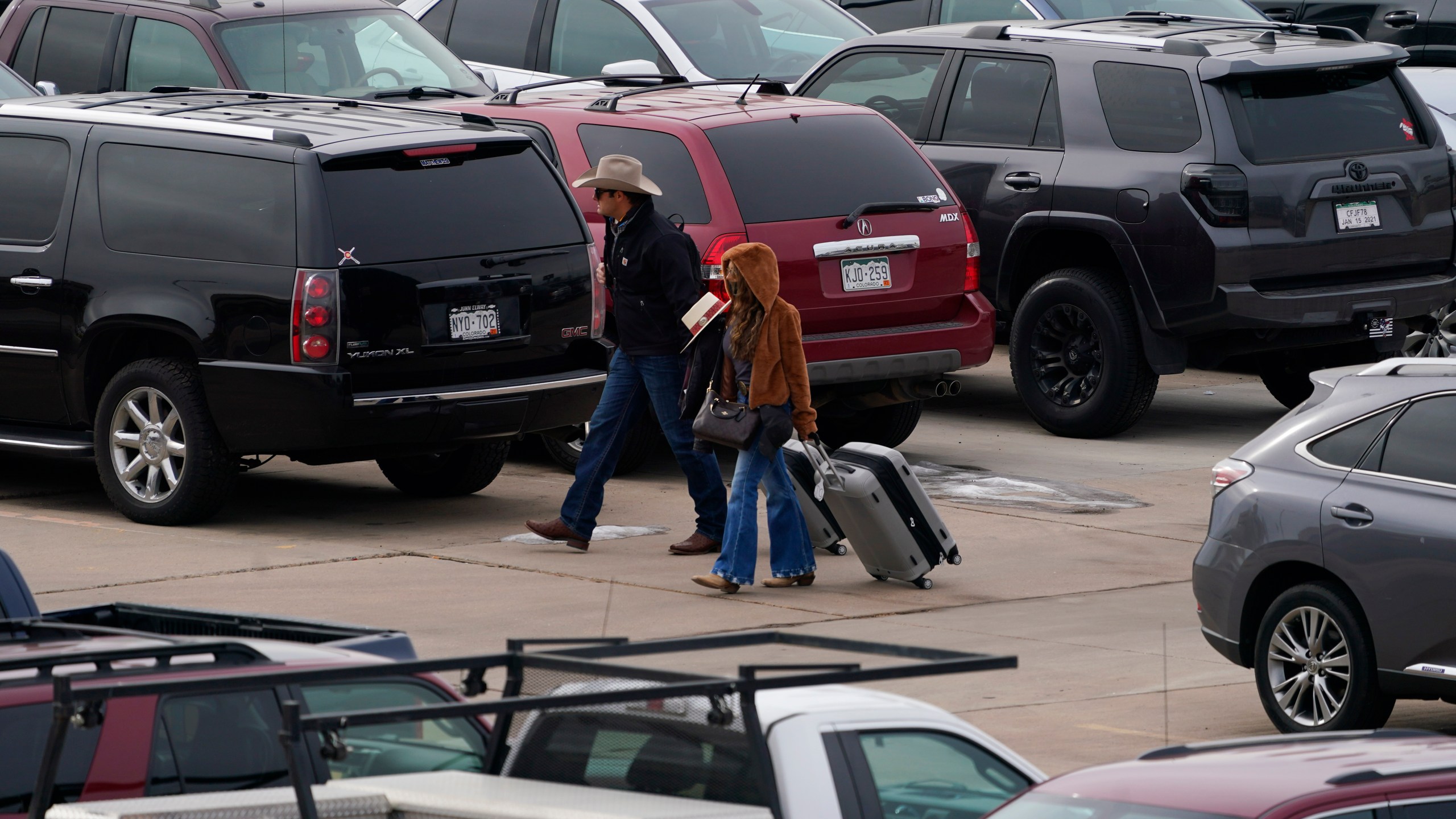 Travelers wade through a parking lot filled with vehicles