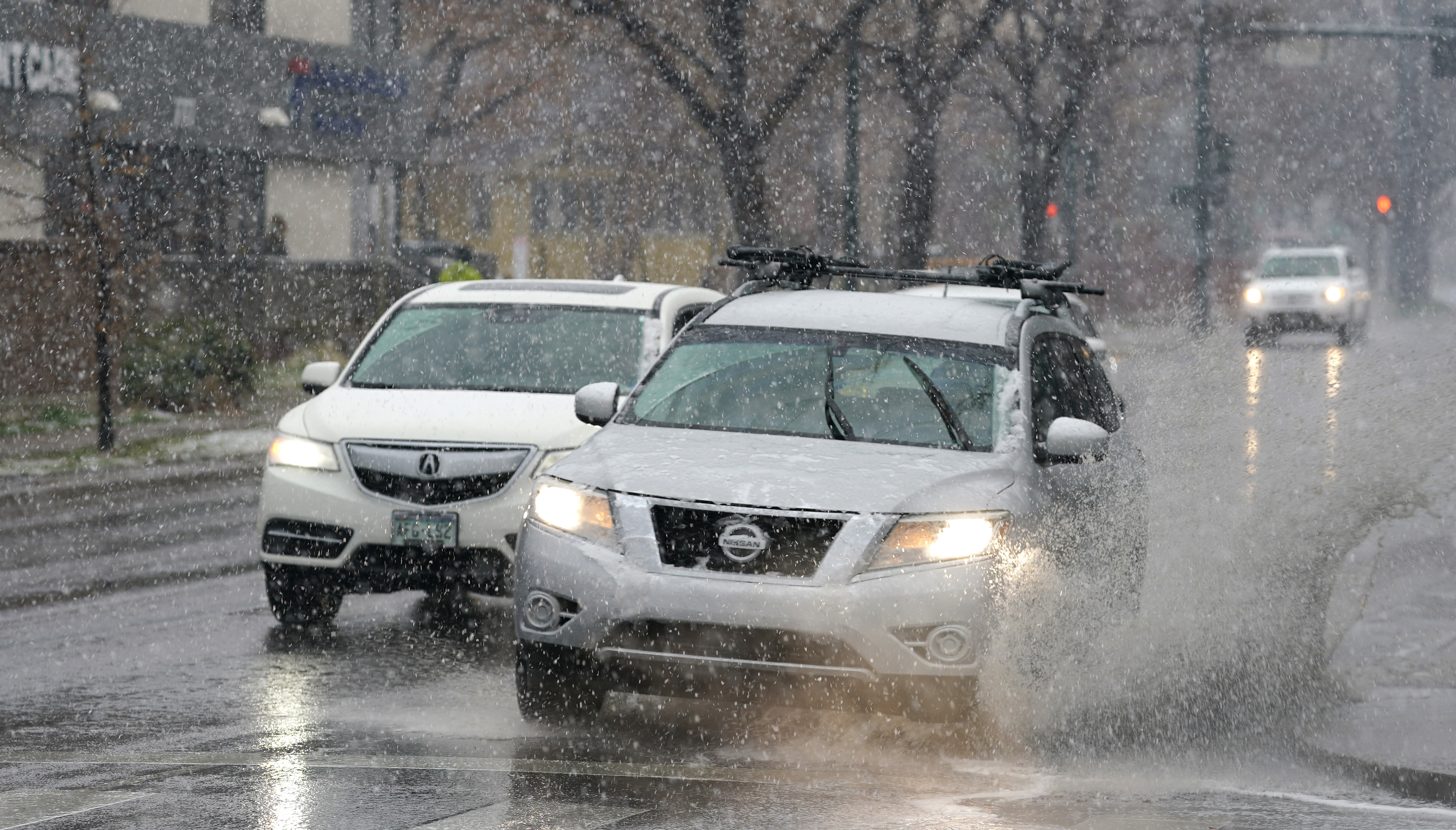 A motorist guides a sports-utility vehicle through a large large puddle in the intersection of westbound Speer Boulevard and Washington Street