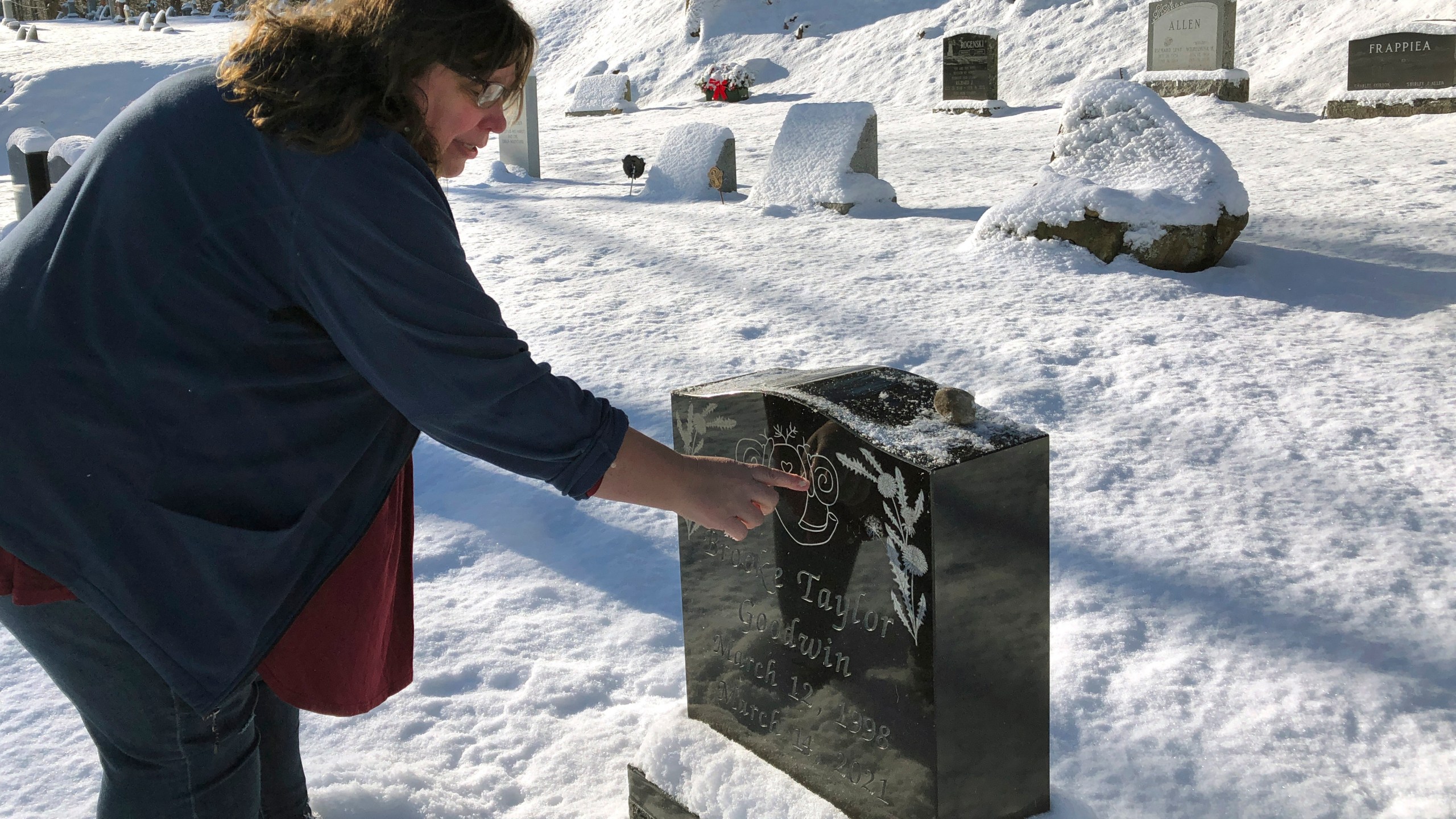 A woman visits the snowy grave of her daughter