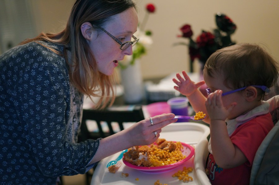 Lauren Hackney feeds her 1-year-old daughter chicken and macaroni during a supervised visit at their apartment