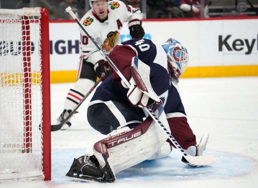 Colorado Avalanche goaltender Alexandar Georgiev, front, makes a glove save of a shot as Chicago Blackhawks center Tyler Johnson covers