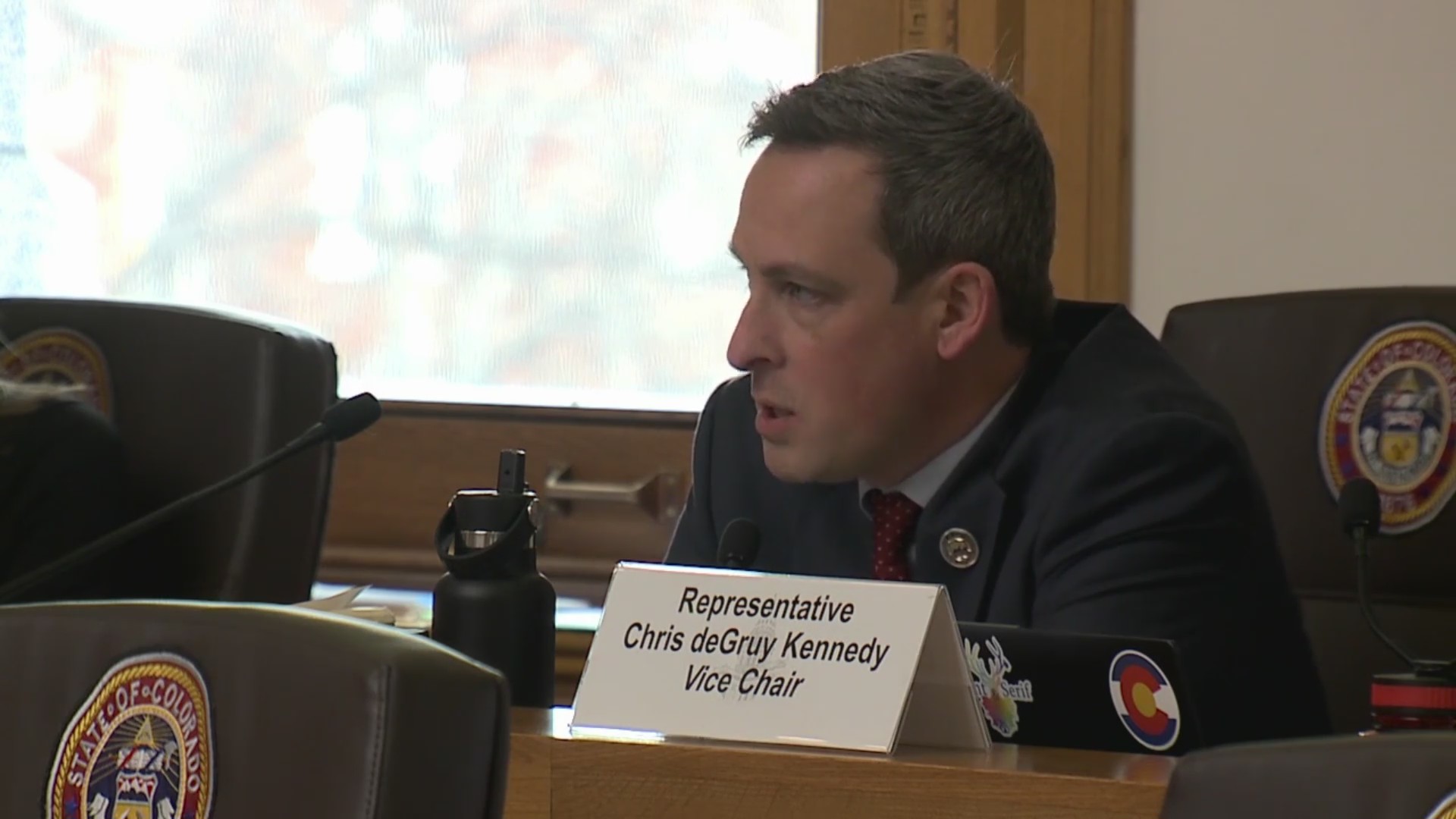 Chris deGruy Kennedy speaks while sitting in a Capitol committee chair during a hearing