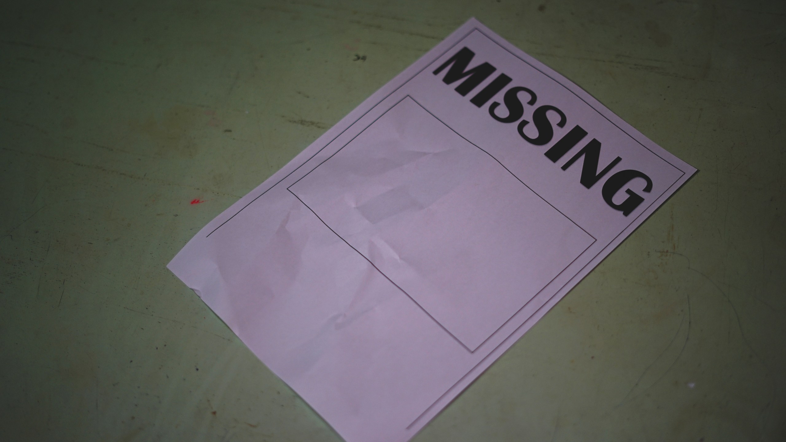 The paper that said Missing lay on the wooden table. Missing person search concept