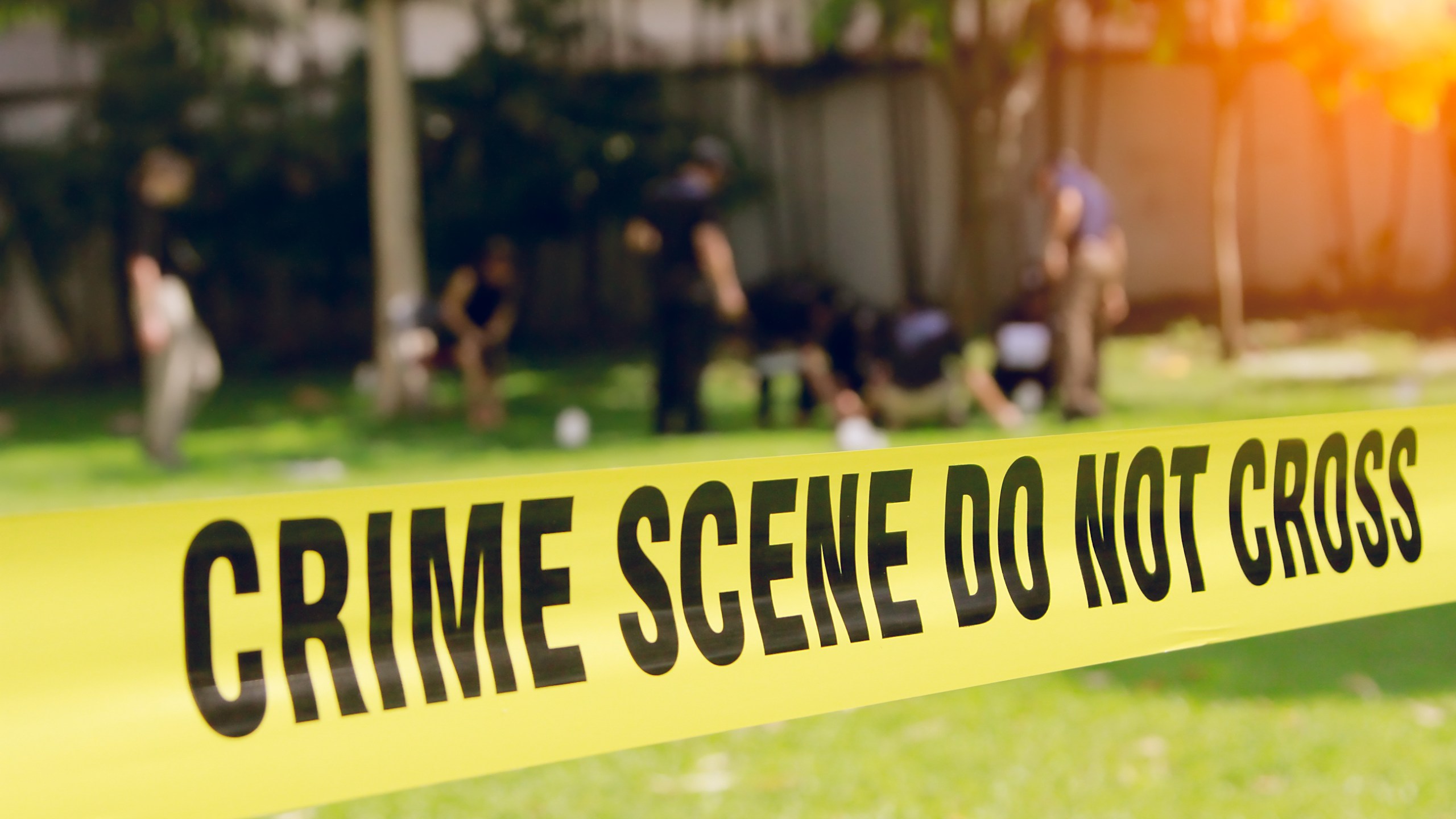 crime scene tape and blurred law enforcement team background