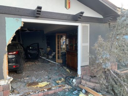 A front window to a building is shattered with the interior exposed and debris all around