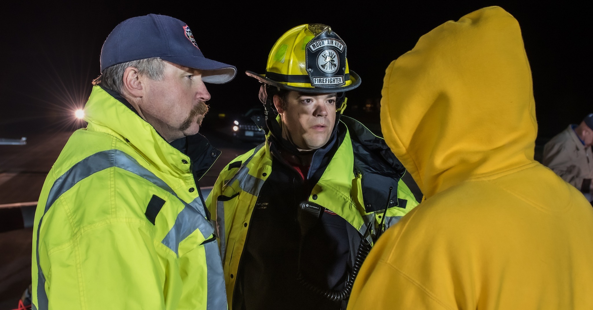 Ben Fournier in fire gear and hat talking with two other people