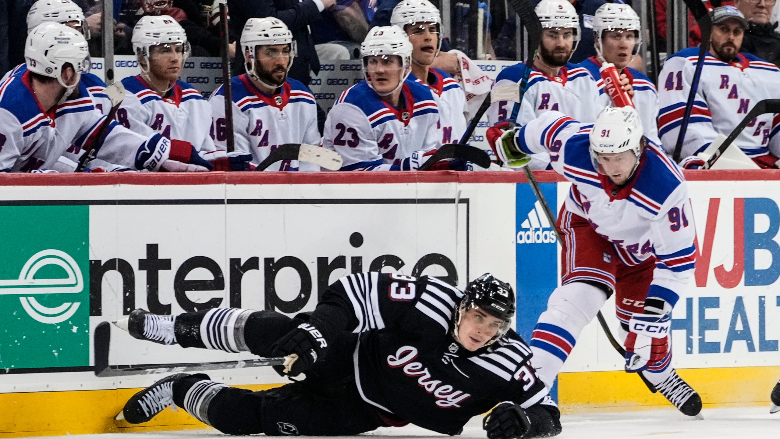 New York Rangers' Vladimir Tarasenko (91) fights for control of the puck with New Jersey Devils' Ryan Graves (33) during the third period of an NHL hockey game Thursday, March 30, 2023, in Newark, N.J. The Devils won 2-1. (AP Photo/Frank Franklin II)