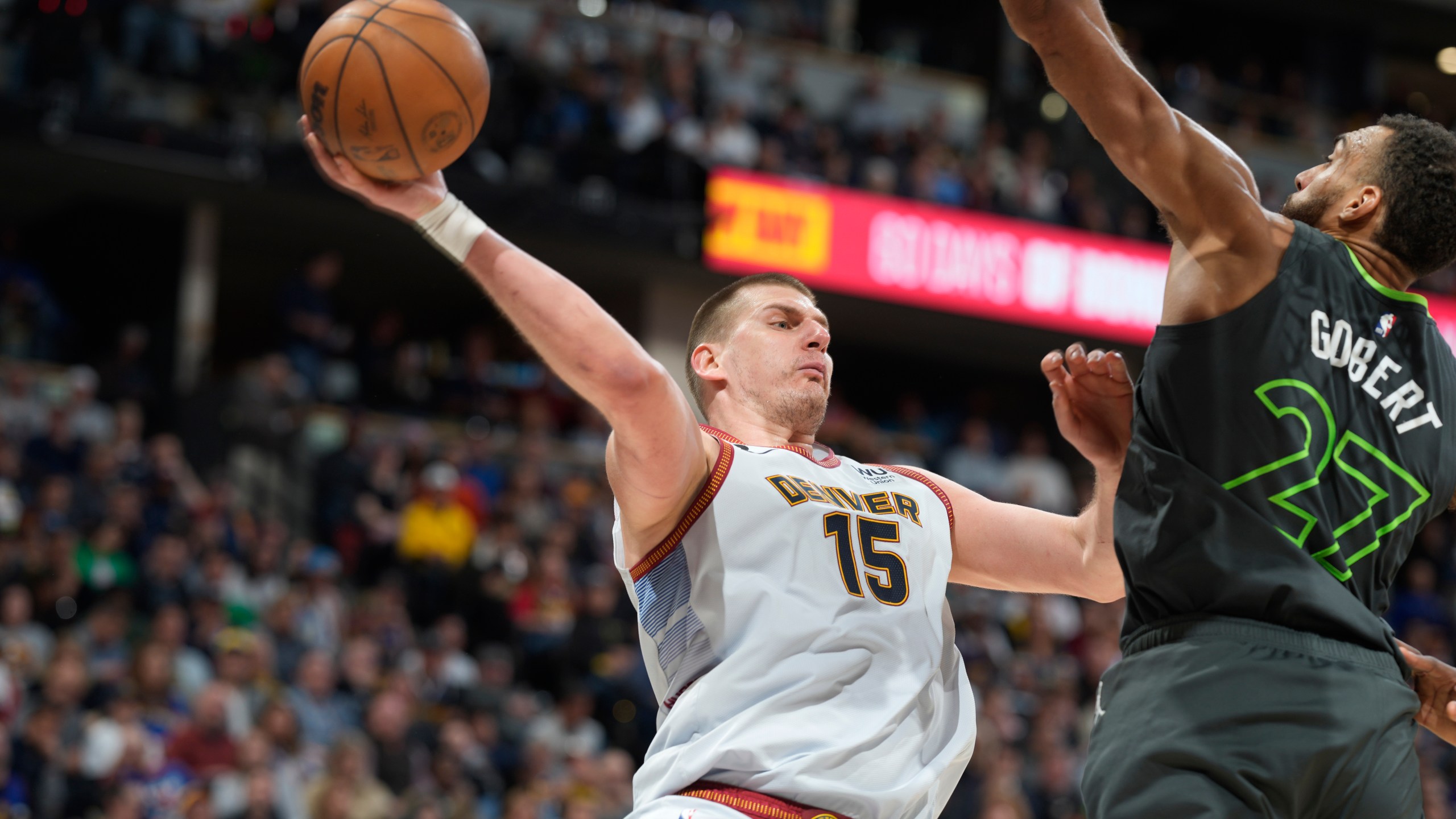 Denver Nuggets center Nikola Jokic, left, passes the ball as Minnesota Timberwolves center Rudy Gobert defends during the second half of Game 5 of an NBA basketball first-round playoff series Tuesday, April 25, 2023, in Denver. (AP Photo/David Zalubowski)