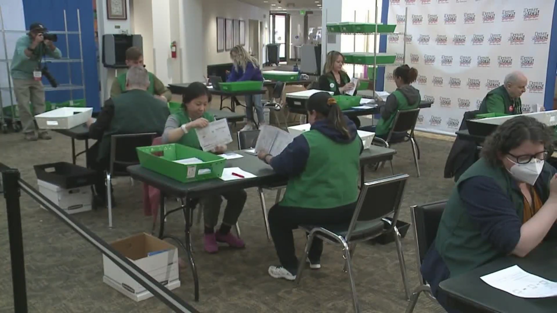 Workers count ballots at tables in a room