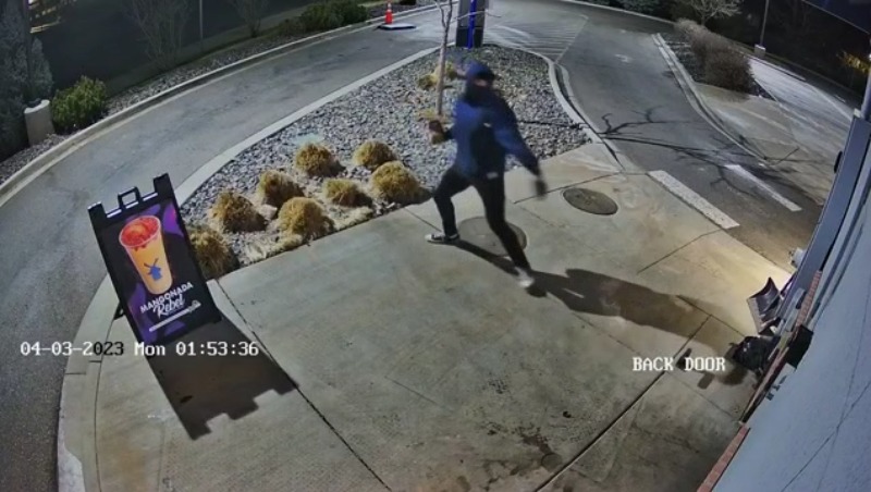 Surveillance video showing a person reaching back, seemingly to launch something