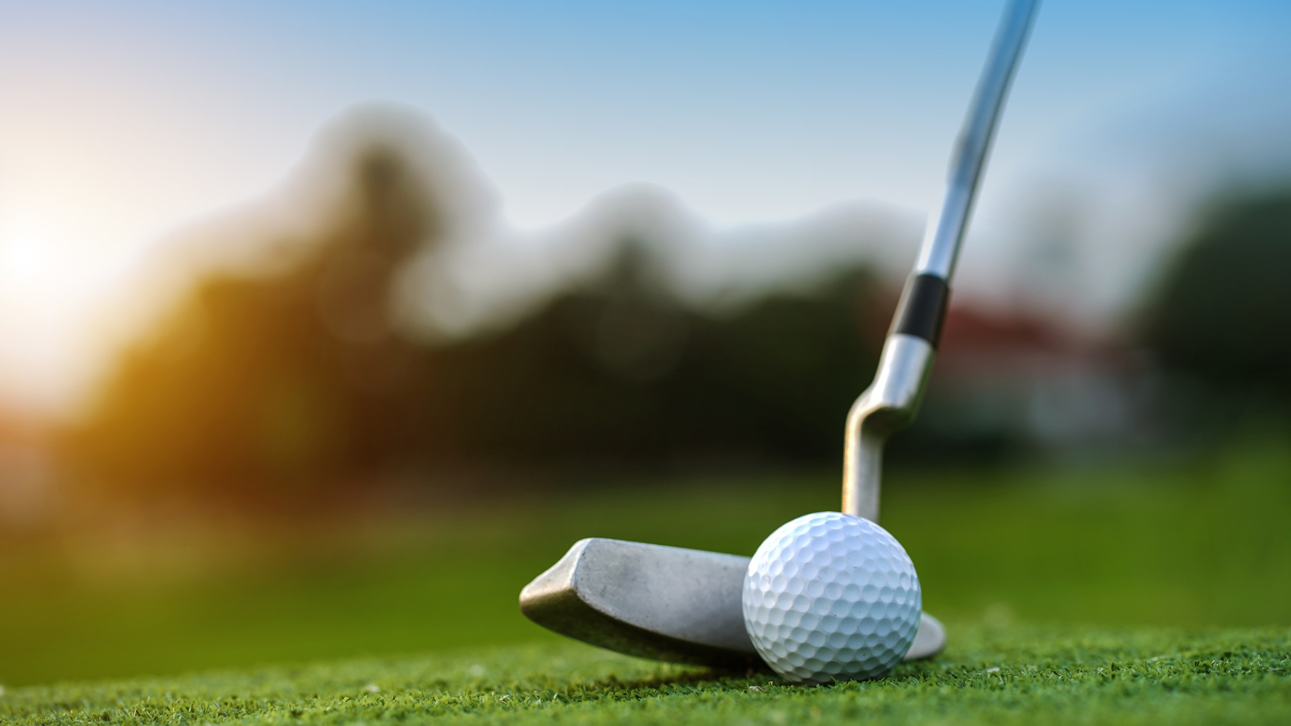 Golf clubs and golf balls on a green lawn in a beautiful golf course with morning sunshine.