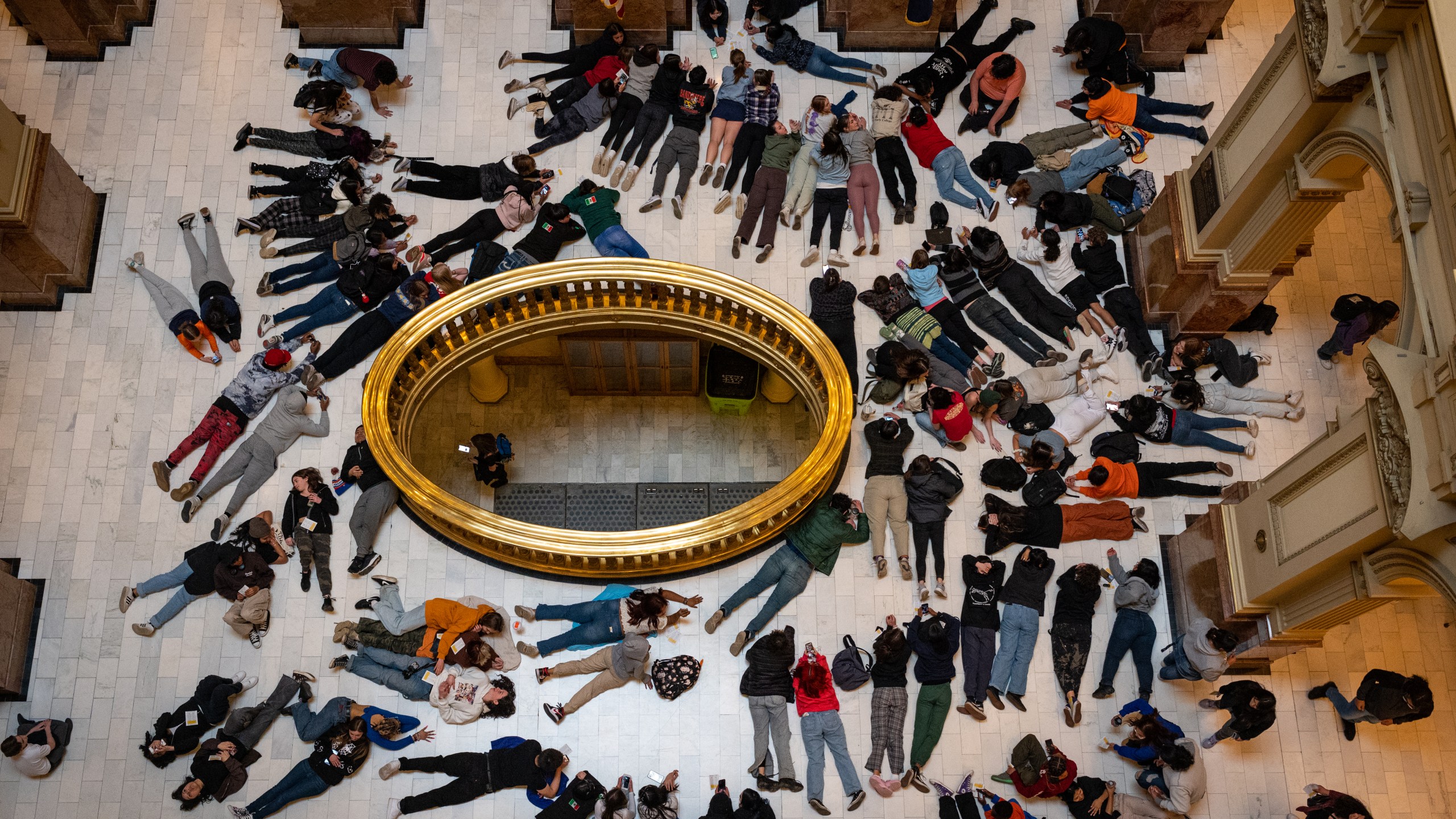 Aerial shot of dozens of teens lying on the ground of the Colorado Capitol