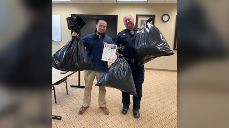 Two people with Douglas County Sheriff's Office hold up garbage bags full of disposed medication from Drug Take-Back Day