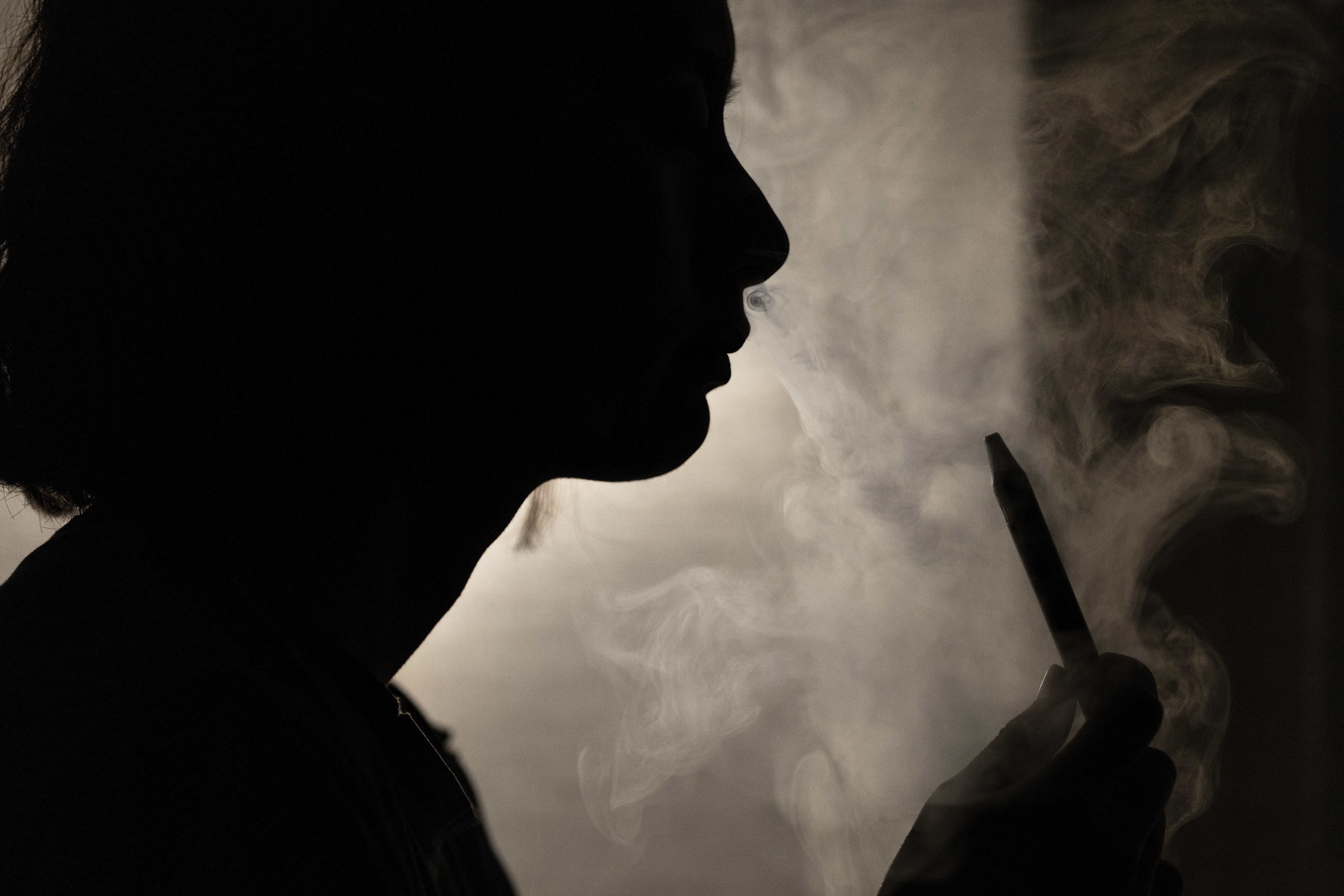 A person poses for a photograph as they vape in Melbourne, March 23, 2023. Recreational vaping will be banned as the government seeks to prevent the next generation from becoming addicted to nicotine, Australia's Health Minister Mark Butler said Tuesday, May 2, 2023.(Diego Fedele/AAP Image via AP)