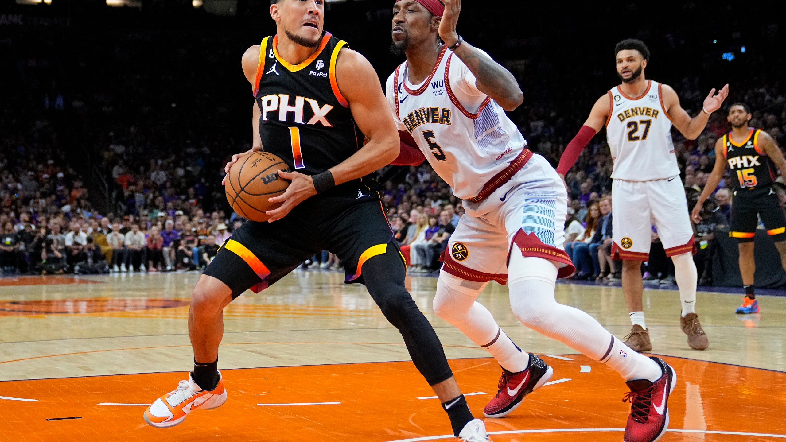 Phoenix Suns guard Devin Booker (1) looks to shoot as Denver Nuggets guard Kentavious Caldwell-Pope (5) defends during the first half of Game 3 of an NBA basketball Western Conference semifinal game, Friday, May 5, 2023, in Phoenix. (AP Photo/Matt York)