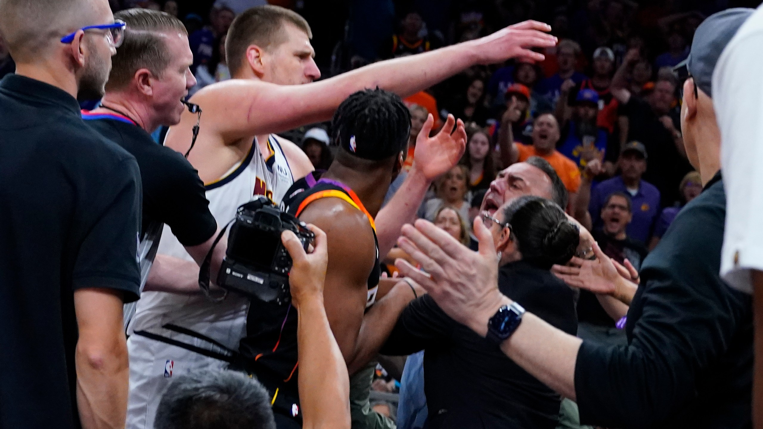 Denver Nuggets center Nikola Jokic get into an altercation in the stands during the first half of Game 4 of an NBA basketball Western Conference semifinal game against the Phoenix Suns, Sunday, May 7, 2023, in Phoenix. (AP Photo/Matt York)