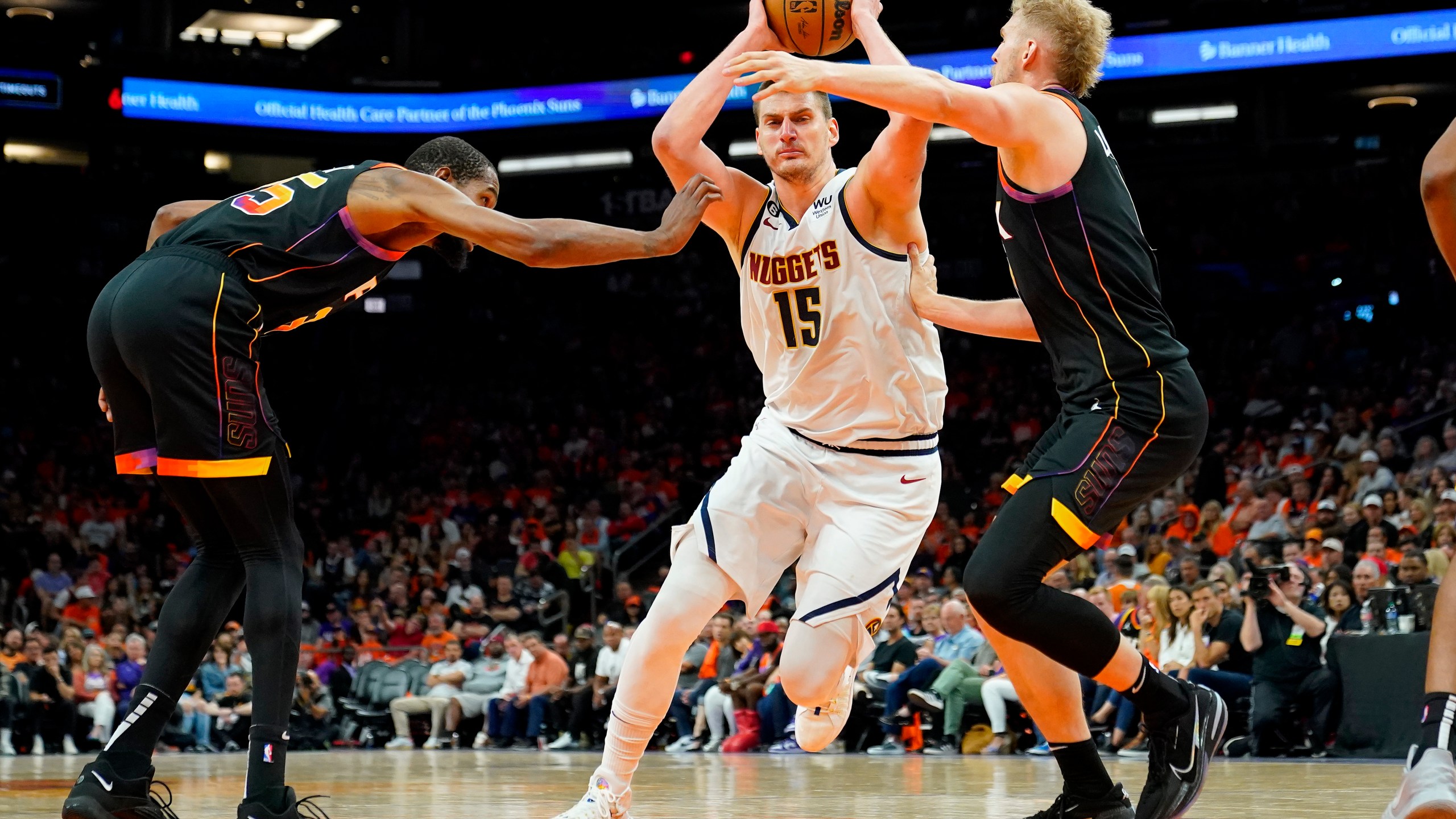 Denver Nuggets center Nikola Jokic (15) drives past Phoenix Suns forward Kevin Durant, left, and center Jock Landale during the second half of Game 6 of an NBA basketball Western Conference semifinal series, Thursday, May 11, 2023, in Phoenix. The Nuggets eliminated the Sun in their 125-100 win. (AP Photo/Matt York)