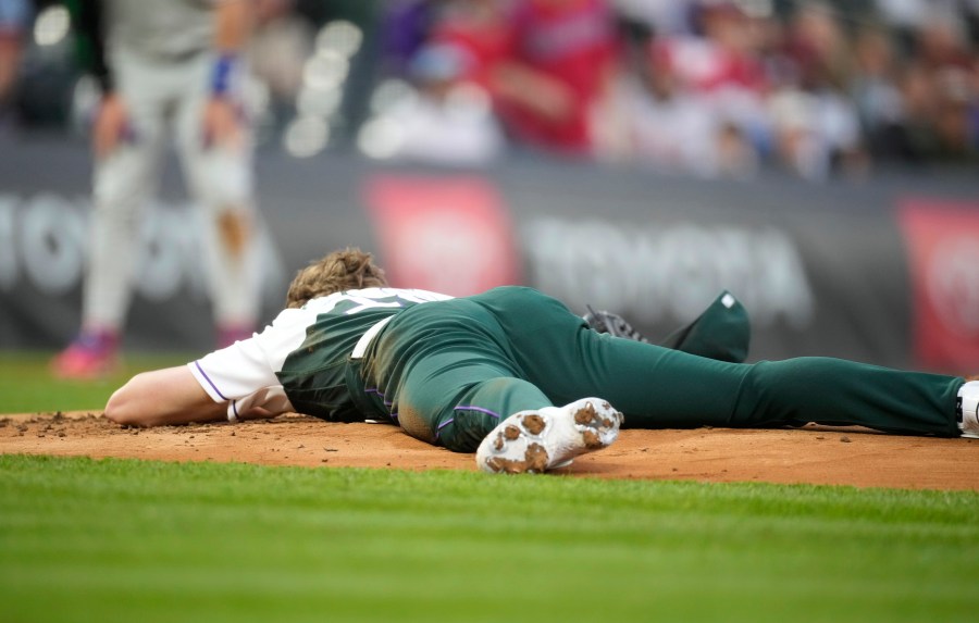 Colorado Rockies starting pitcher Ryan Feltner lies on the mound after getting hit by a single by Philadelphia Phillies' Nick Castellanos during the second inning of a baseball game Saturday, May 13, 2023, in Denver. (AP Photo/David Zalubowski)