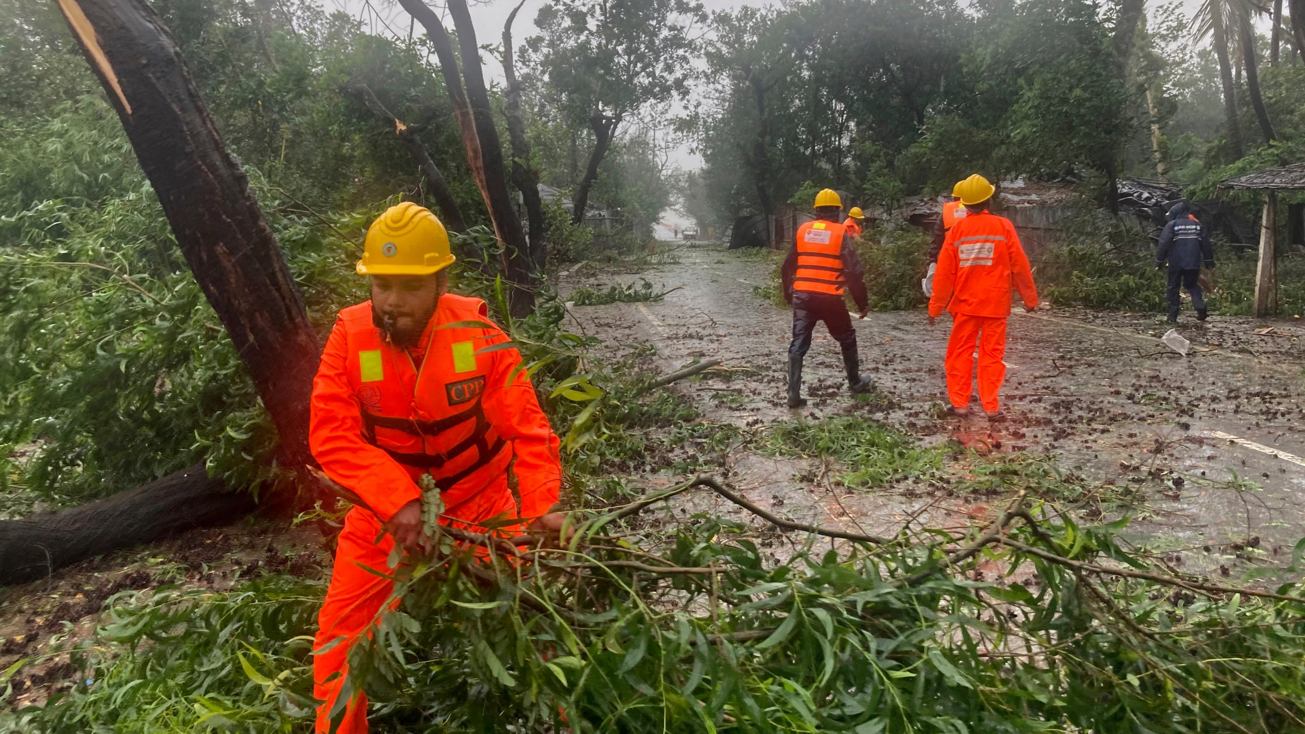 Rescue workers remove the fallen tress after a storm in Teknaf, near Cox's Bazar, Bangladesh, Sunday, May 14, 2023. Bangladesh and Myanmar braced Sunday as a severe cyclone started to hit coastal areas and authorities urged thousands of people in both countries to seek shelter. (AP Photo/Al-emrun Garjon)