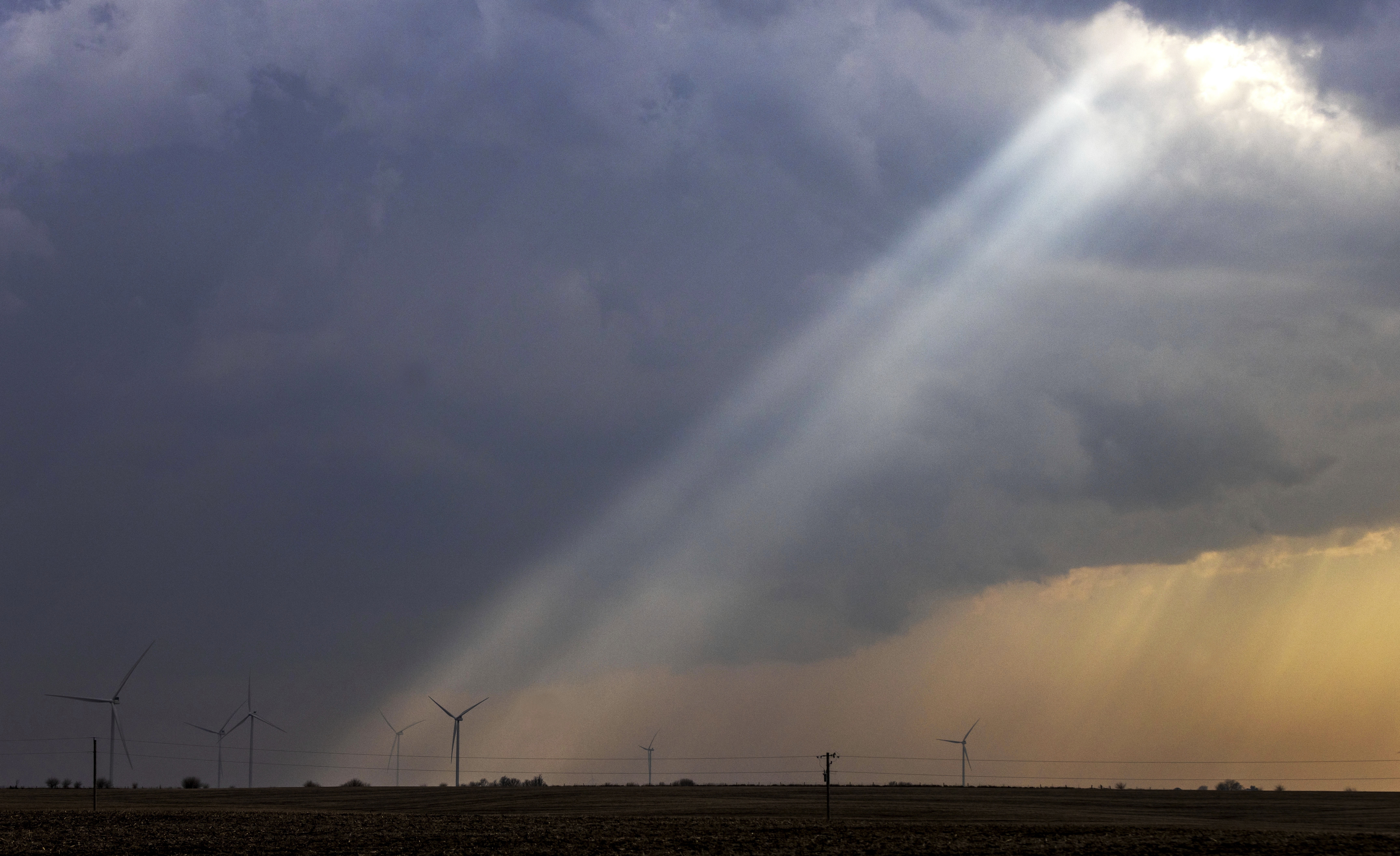 FILE - Sunlight filters through storm clouds onto a wind turbine as severe weather rolls through the midwest on April 4, 2023, south of Stuart, Iowa. The U.S. Department of Agriculture announced a nearly $11 billion investment on Tuesday, May 16, to help bring affordable clean energy to rural communities throughout the country. (Chris Machian/Omaha World-Herald via AP, File)