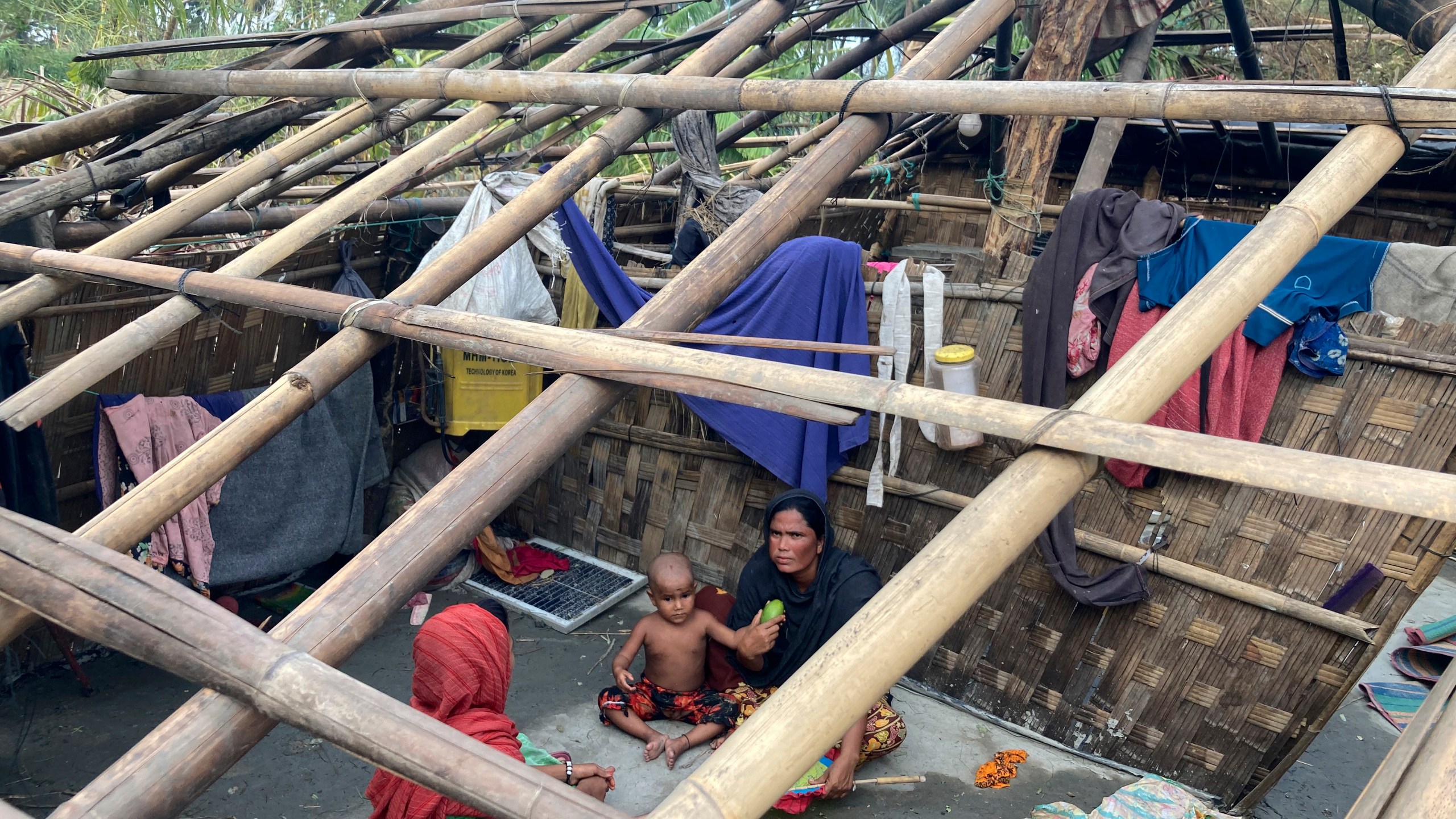 FILE- A family rests inside their home damaged by Cyclone Mocha at Saint Martin island in Cox's Bazar, Bangladesh, Monday, May 15, 2023. Early warnings from weather agencies and preparedness by local governments and aid agencies likely saved thousands of lives from a power Cyclone in that might have been claimed by the cyclone that slammed into the joint coastline of Bangladesh and Myanmar on Sunday. But there are concerns over the large number of people still unaccounted for in regions where preventative action was lacking. (AP Photo/Al-emrun Garjon, File)