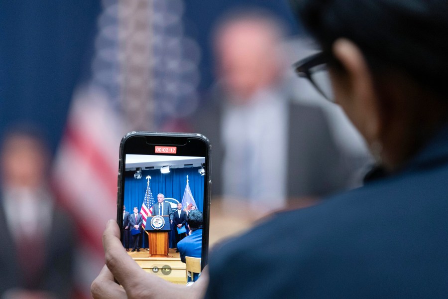 Assistant Secretary for Export Enforcement Matthew Axelrod of the U.S. Commerce Department, is seen on cell phone as he speaks during a news conference at the Department of Justice in Washington, Tuesday, May 16, 2023. (AP Photo/Jose Luis Magana)