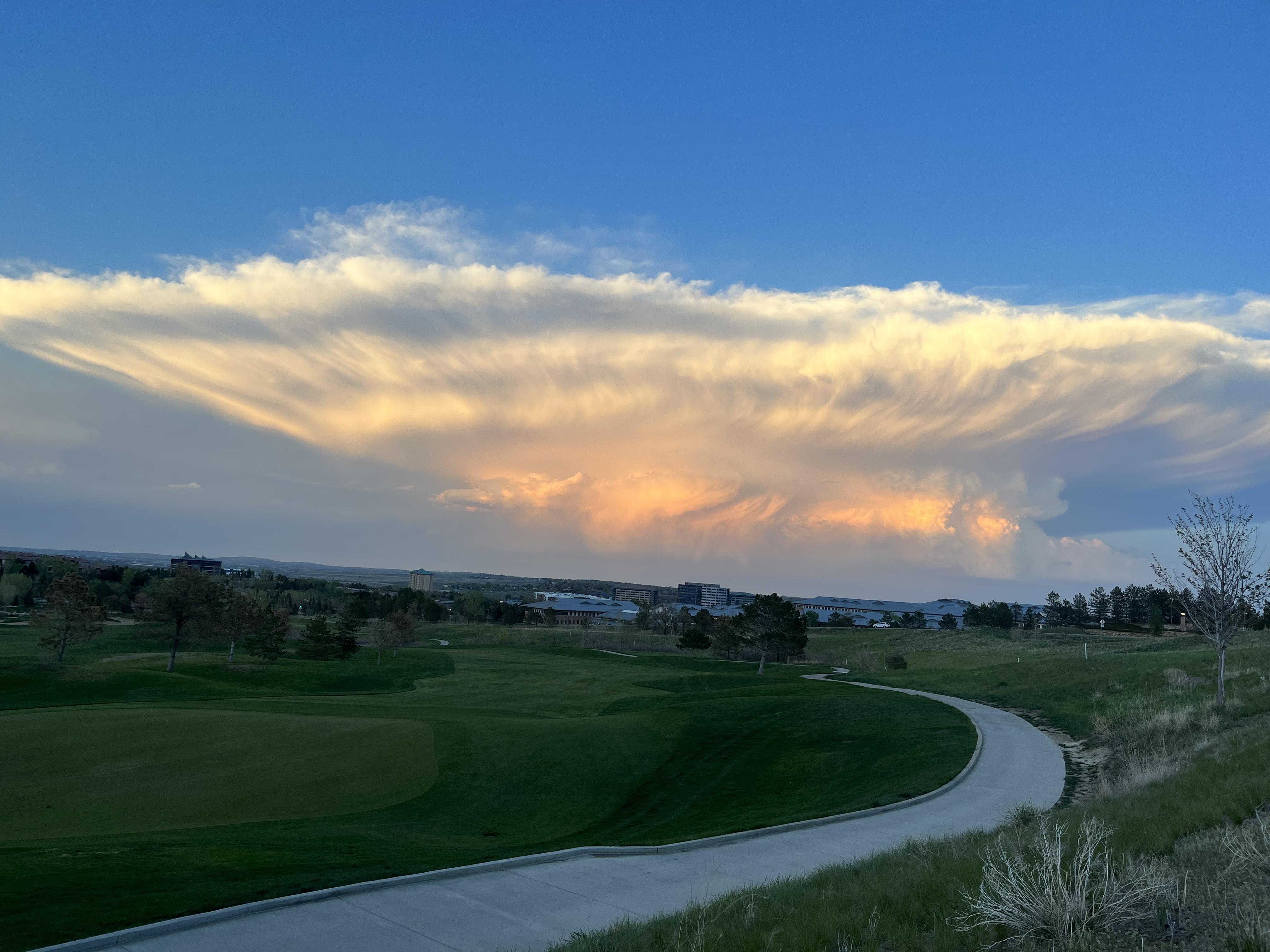 A cloud has pockets toward the bottom and expands across the horizon high in the sky.