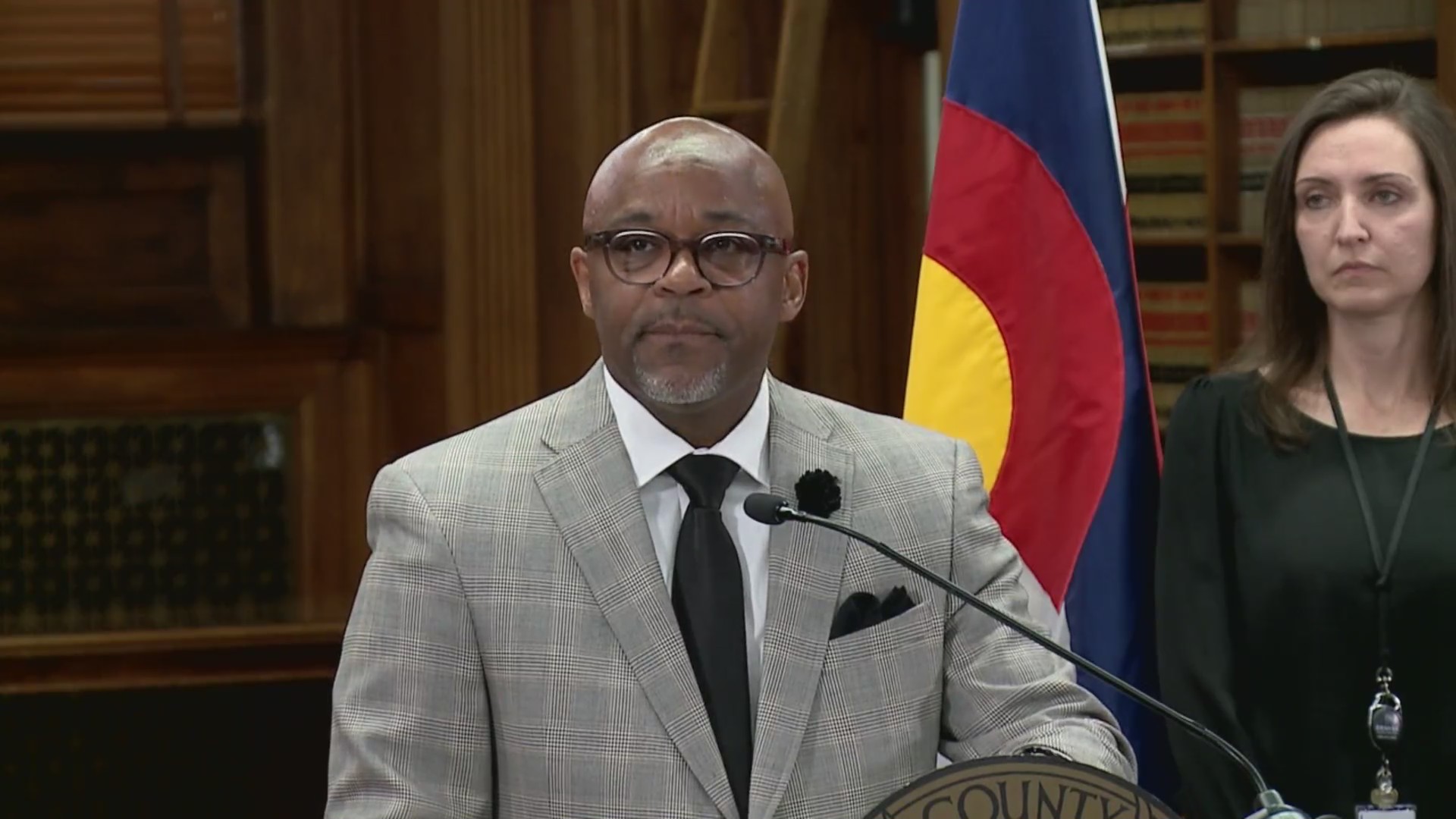 Denver Mayor Michael Hancock stands at a lectern in front of a Colorado flag