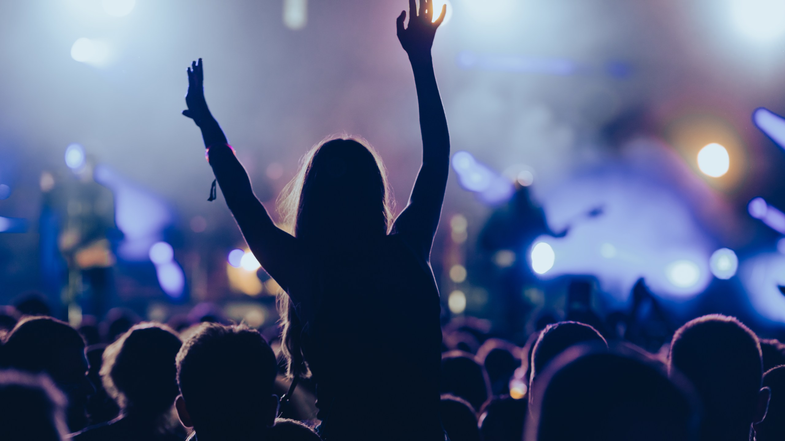 Silhouette of a woman with raised hands on a concert