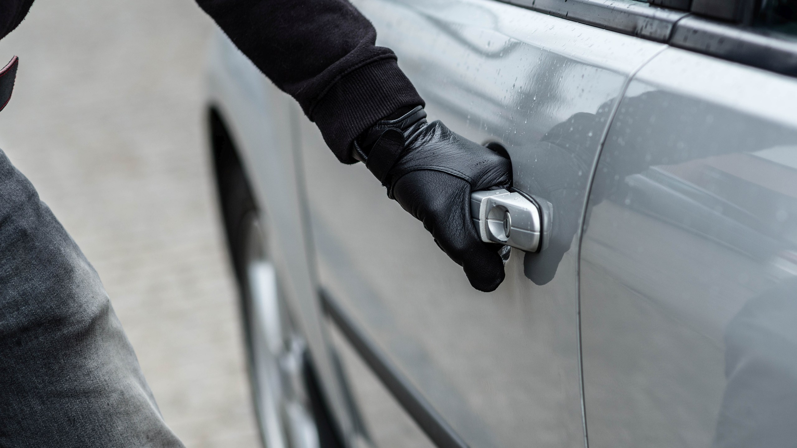 car thief hand pulling the handle of a car