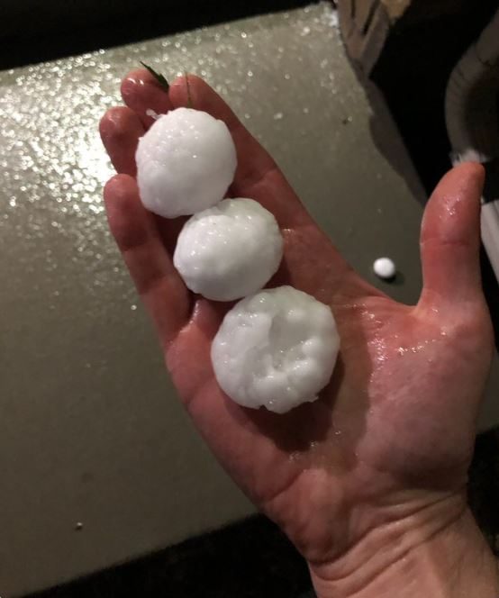 Three piece of golf-ball sized hail in the palm of a hand