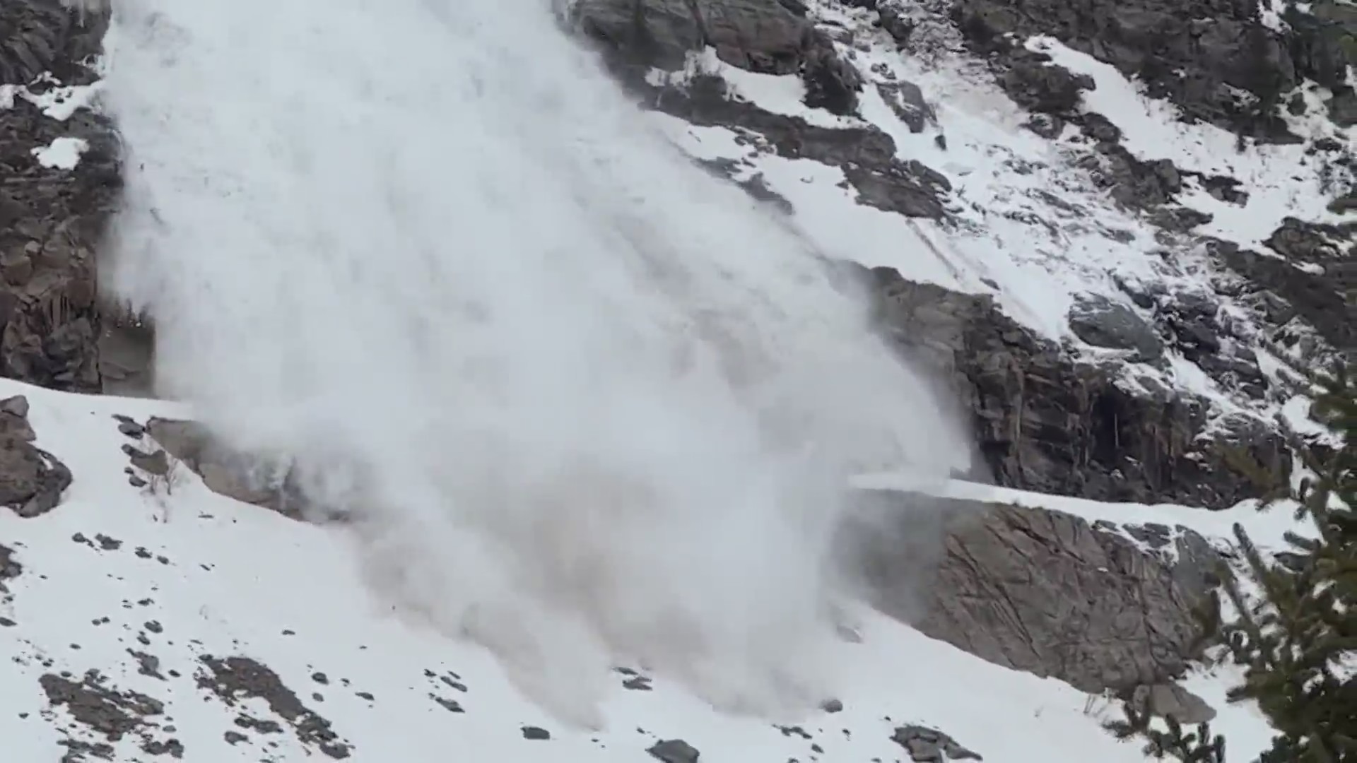 Avalanche falls down a snowy mountainside onto a highway