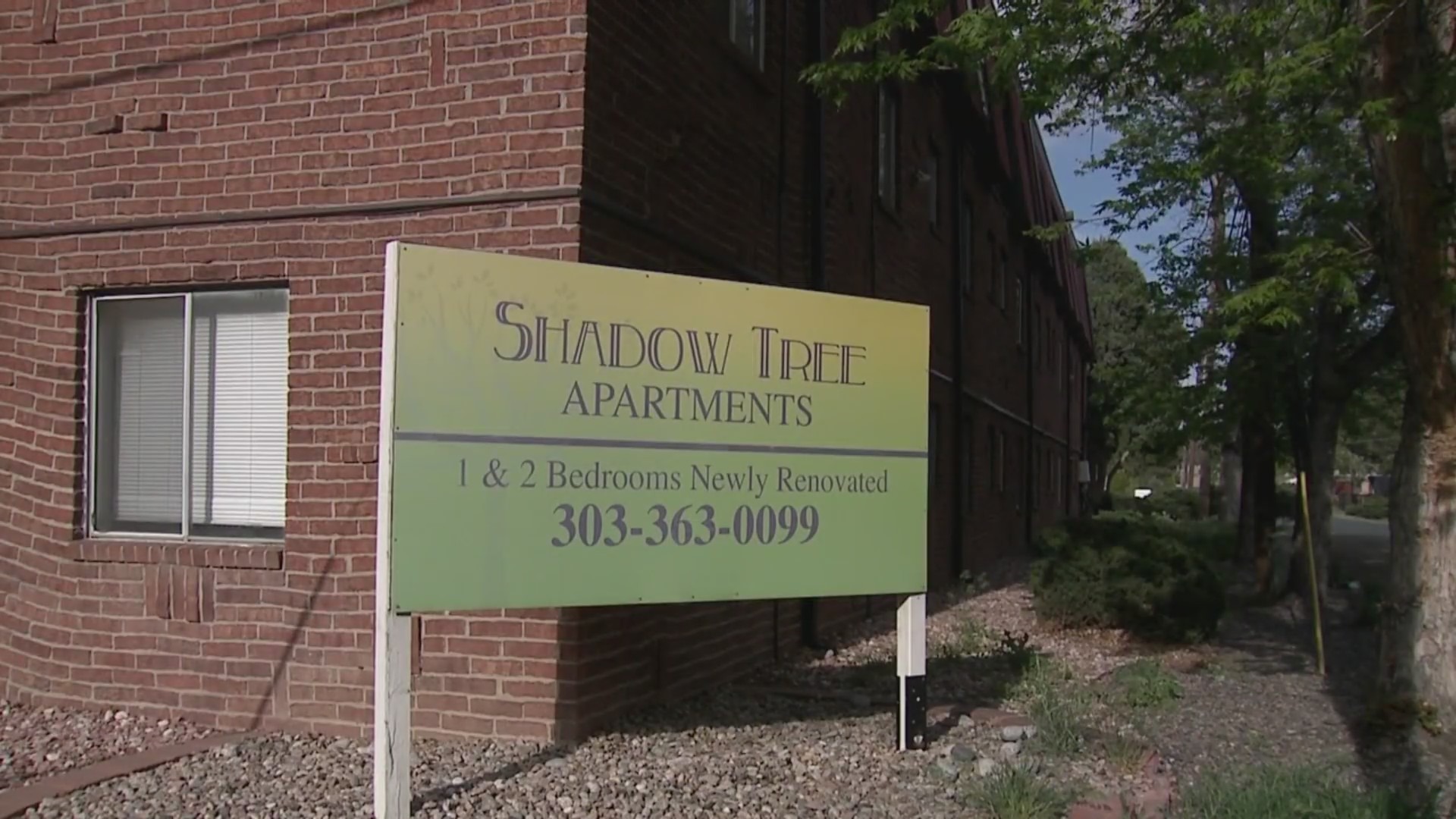 A sign outside of a brick building reads "Shadow Tree Apartments 1 & 2 Bedrooms Newly Renovated 303-363-0099"