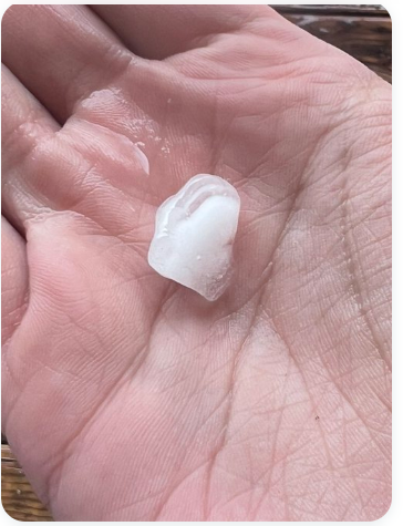 A piece of hail is held in hand.