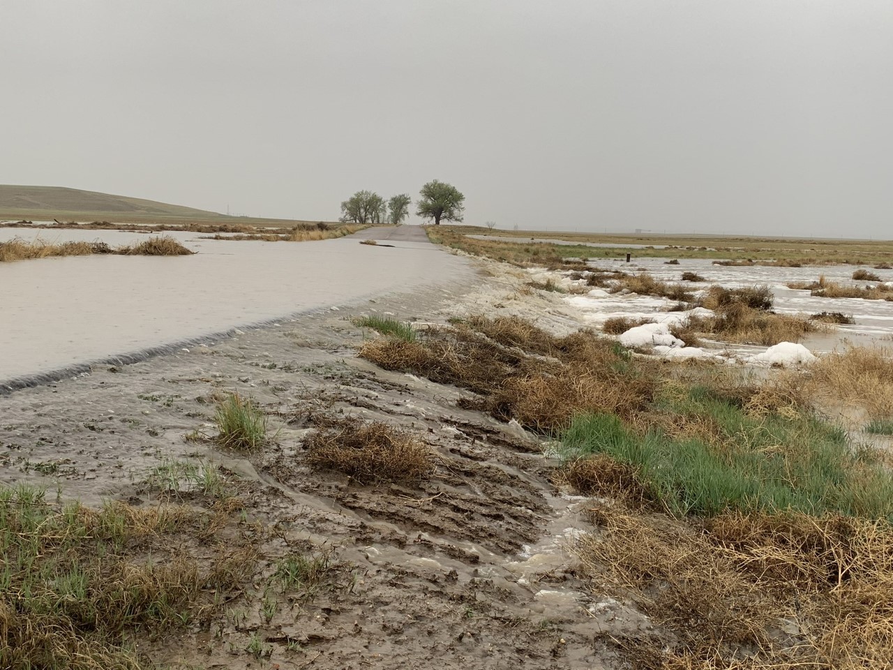 Flood water is flowing over a road.